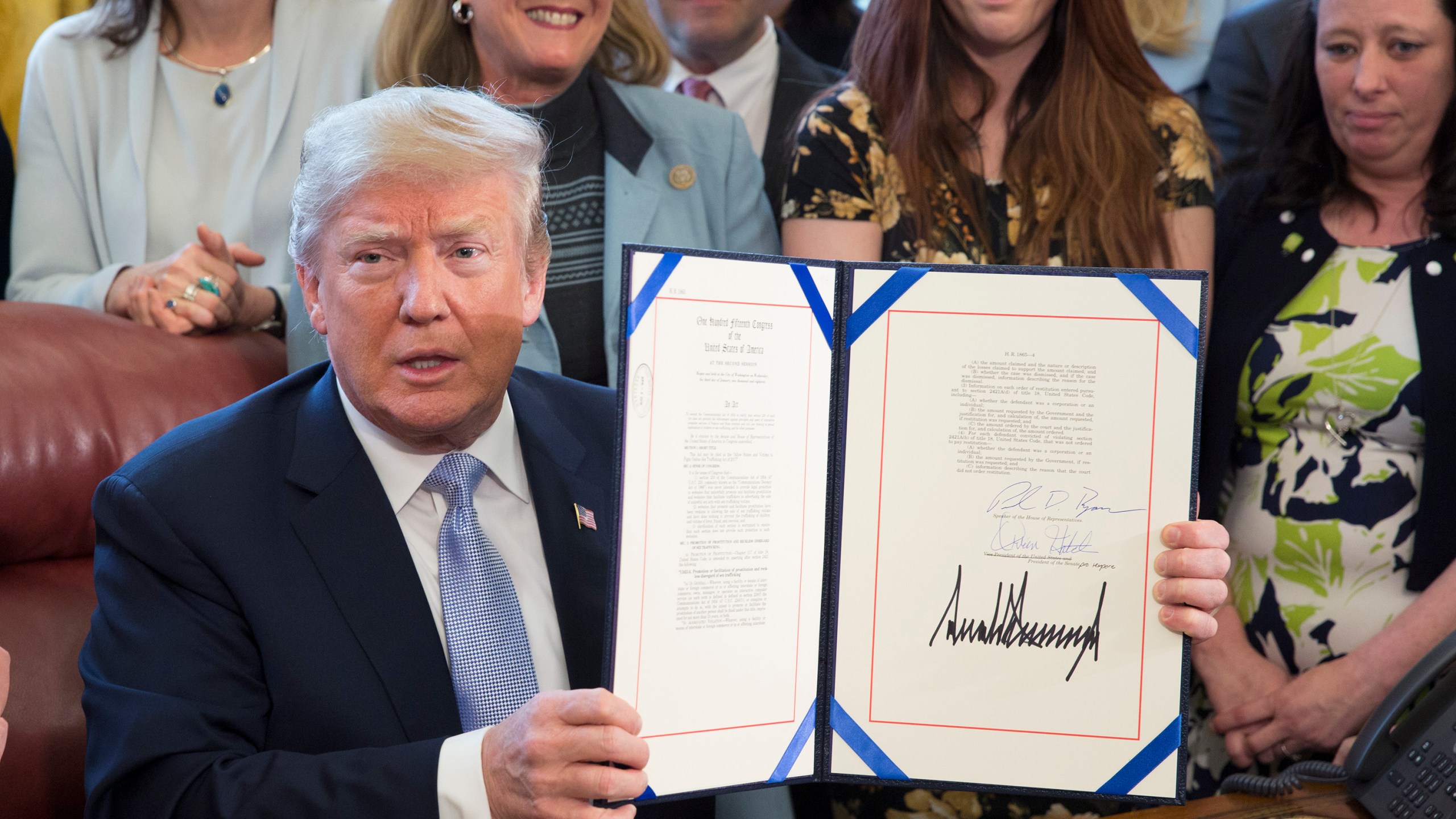 Donald Trump displays H.R. 1865, the "Allow States and Victims to Fight Online Sex Trafficking Act of 2017" after signing it into law at the White House on April 11, 2018. (Credit: Chris Kleponis-Pool/Getty Images)