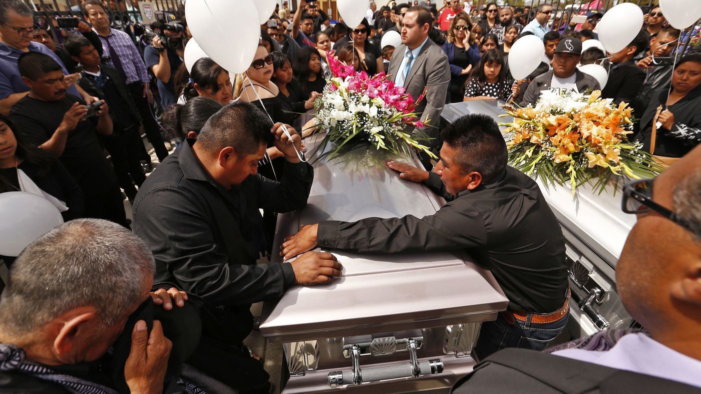 The brothers of Santos Hilario Garcia, who was killed in a crash while fleeing ICE in Kern County along with his partner, Marcelina Garcia Perfecto, are seen standing around the couple's caskets on the day of their funeral service at Our Lady of Guadalupe Church in Delano on April 2, 2018. (Credit: Al Seib / Los Angeles Times)