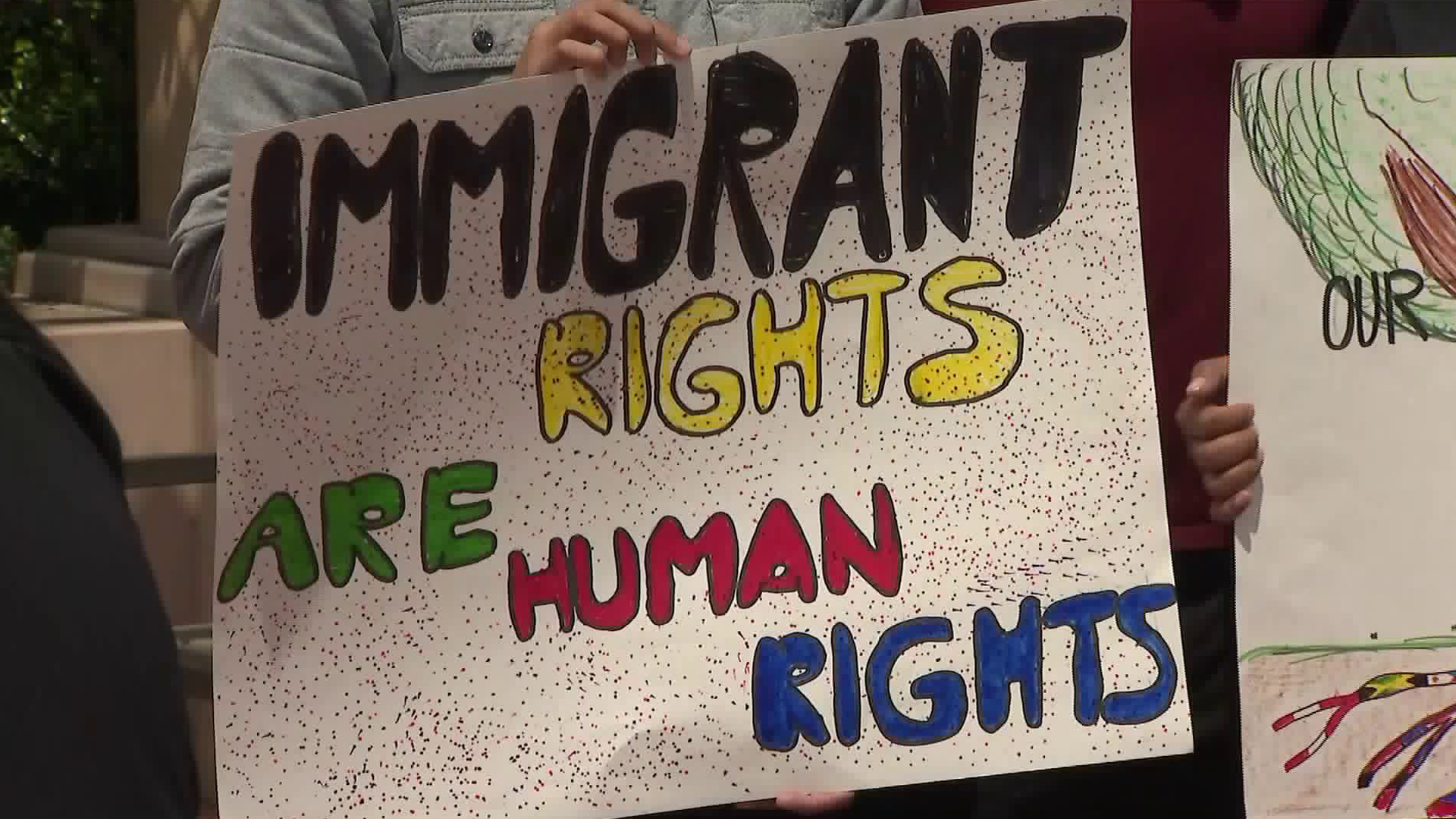 A DACA supporter holds a sign at a rally outside of a court hearing in Pasadena on May 15, 2018. (Credit: KTLA)