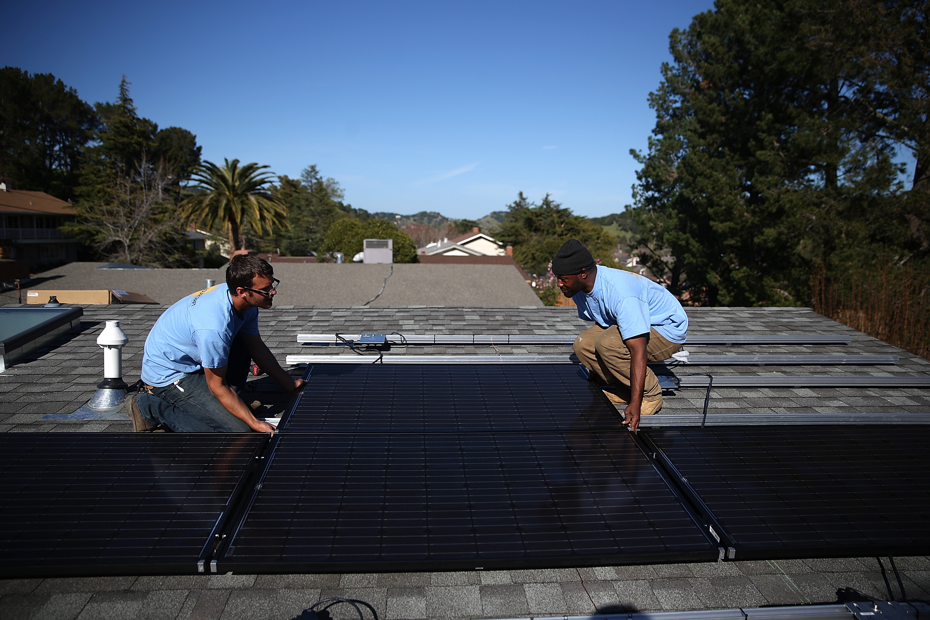 SolarCraft workers Craig Powell (left) and Edwin Neal install solar panels on the roof of a home in San Rafael, California on February 26, 2015. (Credit: Justin Sullivan/Getty Images)