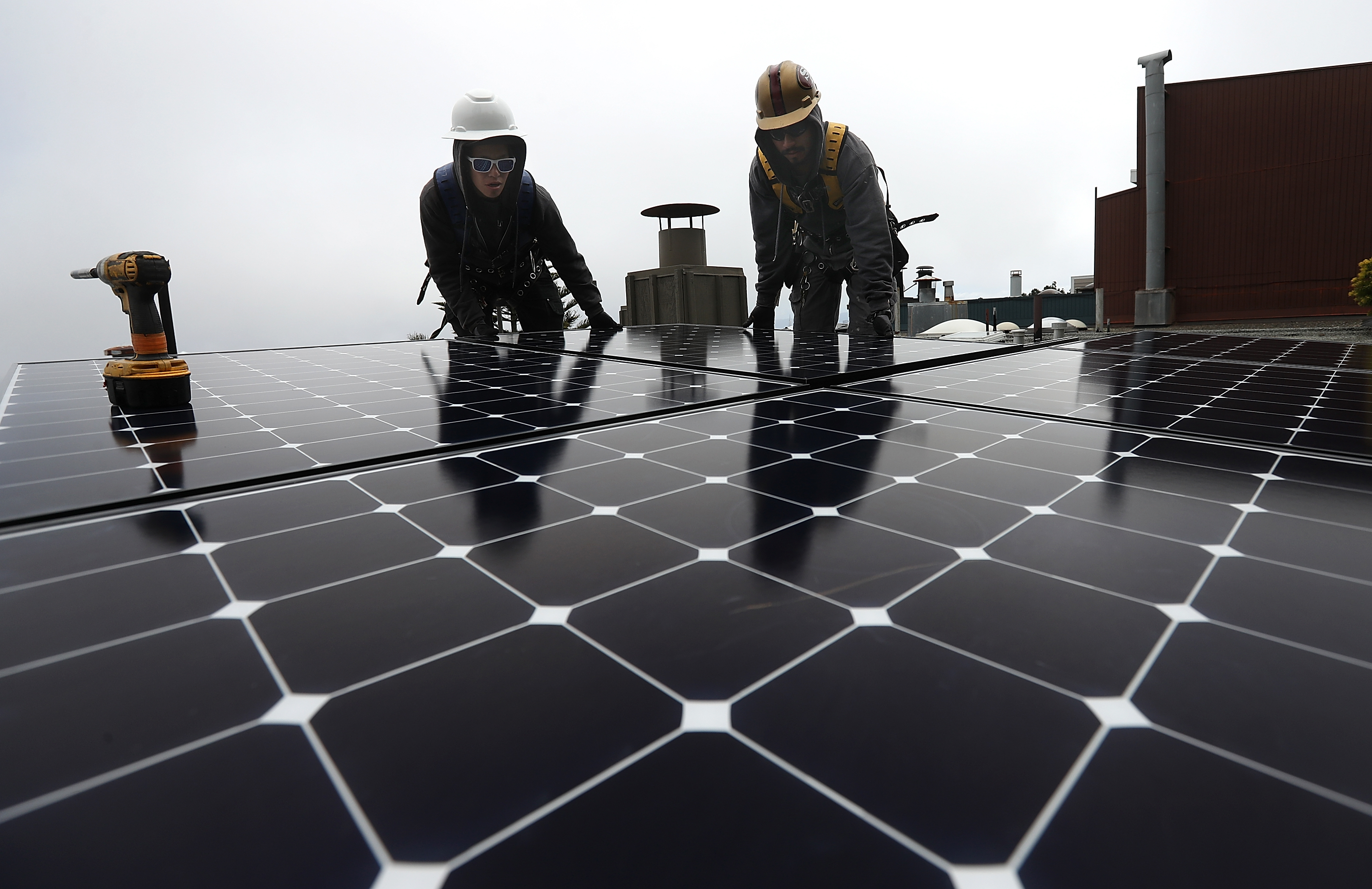 Luminalt solar installers Pam Quan, left, and Walter Morales, right, install solar panels on the roof of a home on May 9, 2018, in San Francisco. (Credit: Justin Sullivan / Getty Images)