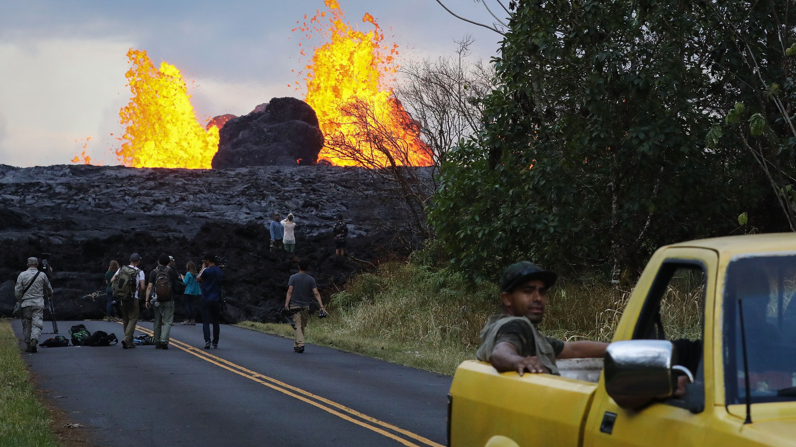 Onlookers and media gather as lava from a Kilauea volcano fissure erupts in Leilani Estates, in Pahoa on Hawaii's Big Island, May 26, 2018. (Credit: Mario Tama / Getty Images)