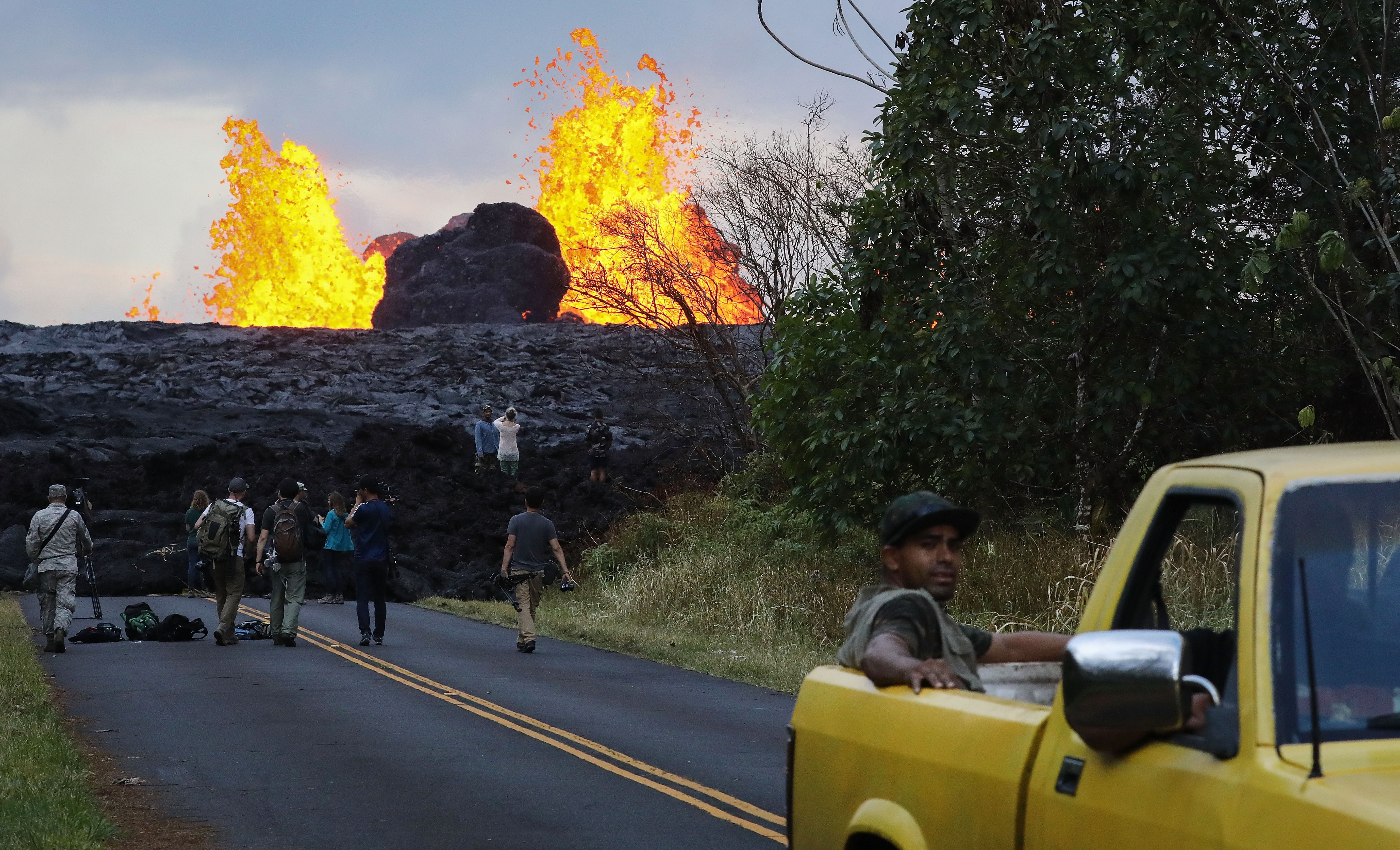 Onlookers and media gather as lava from a Kilauea volcano fissure erupts in Leilani Estates, in Pahoa on Hawaii's Big Island, May 26, 2018. (Credit: Mario Tama / Getty Images)