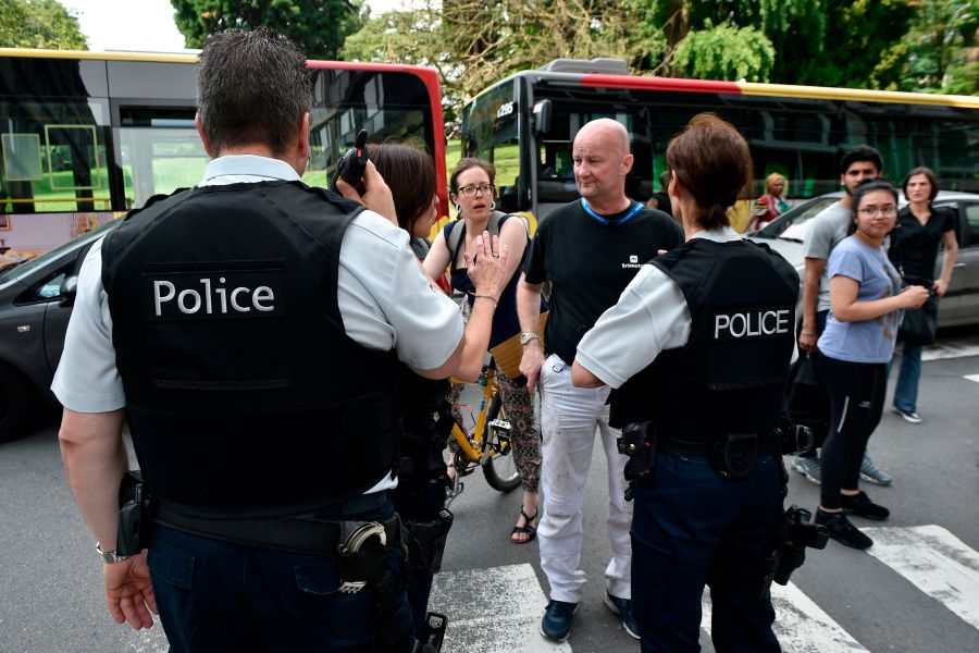 A police officer speaks with parents of children at a nearby high school in the eastern Belgian city of Liege on May 29, 2018. (Credit: JOHN THYS/AFP/Getty Images)