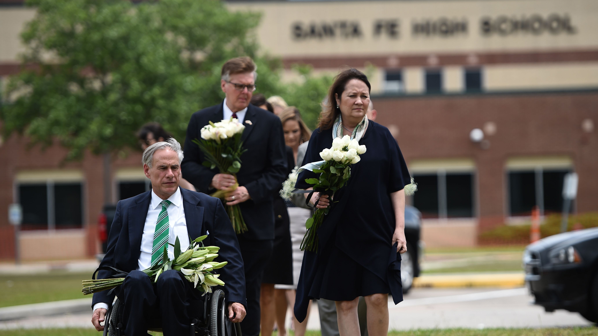 Texas Gov. Greg Abbott, his wife Cecilia Abbott, Lt. Gov. Dan Patrick and other officials bring flowers for a makeshift memorial on the grounds of Santa Fe High School on May, 20, 2018, in Santa Fe, Texas. (Credit: BRENDAN SMIALOWSKI/AFP/Getty Images)