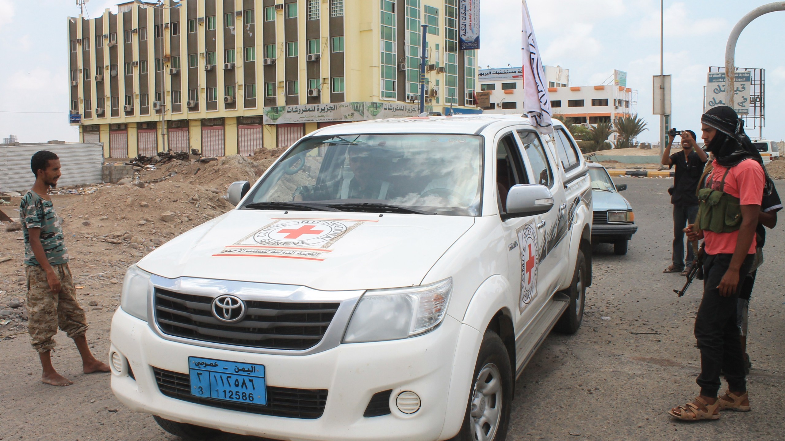 An International Committee of the Red Cross (ICRC) vehicle drives past Yemeni fighters loyal to President Abedrabbo Mansour Hadi, on April 15, 2015, in the southern port city of Aden. (Credit Saleh Al-Obeidi/AFP/Getty Images)