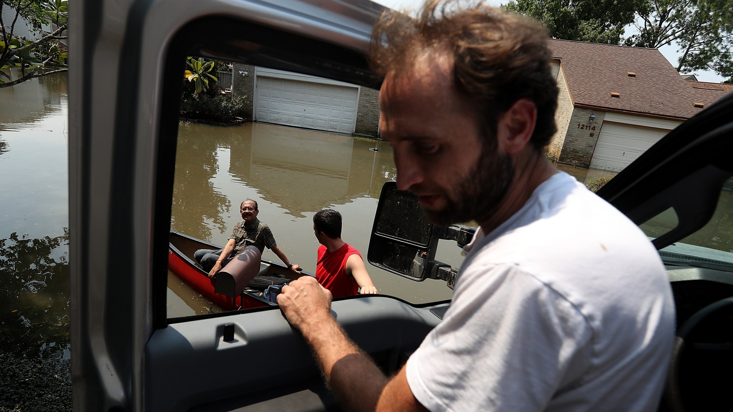 Chris Ginter (right) talks to residents on a boat in a flooded neighborhood on Sept. 6, 2017 in Houston. (Credit: Justin Sullivan/Getty Images)