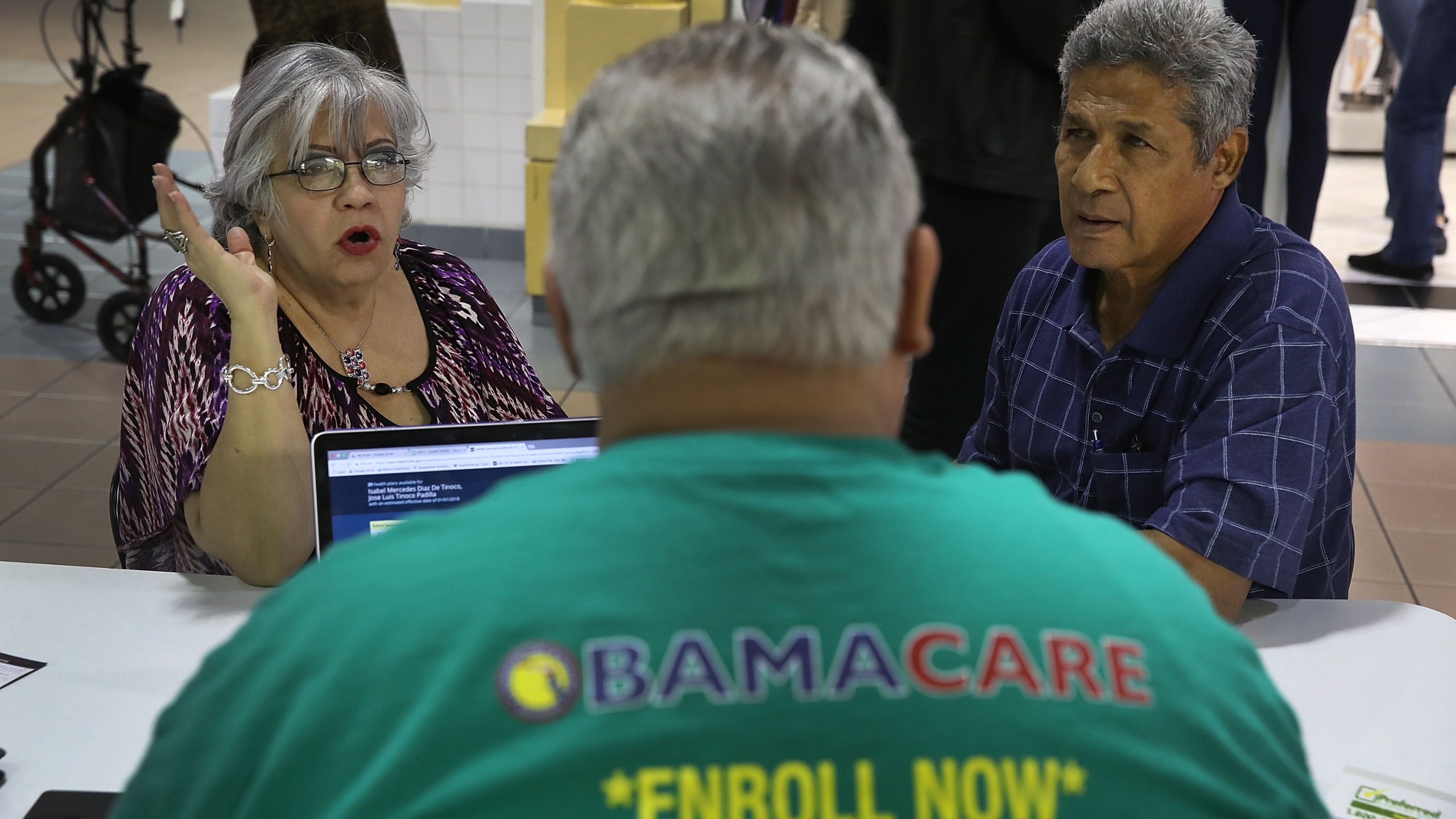 Isabel Diaz Tinoco, left, and Jose Luis Tinoco speak with Otto Hernandez, an insurance agent from Sunshine Life and Health Advisors, as they shop for insurance under the Affordable Care Act at a store setup in the Mall of Americas on Nov. 1, 2017, in Miami, Florida. (Credit: Joe Raedle/Getty Images)