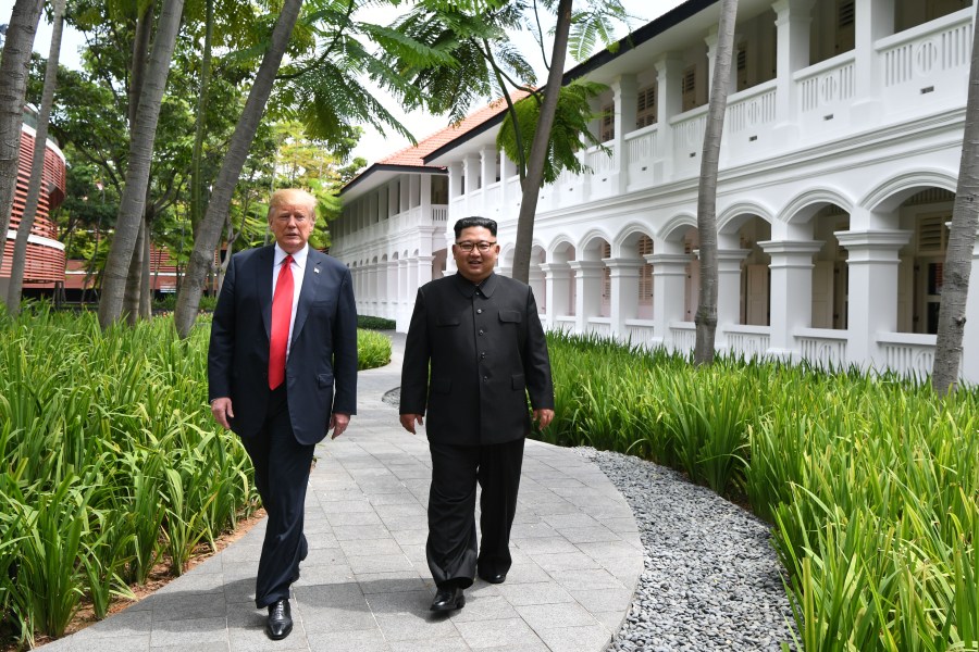 North Korea's leader Kim Jong Un, right, walks with President Donald Trump, left, during a break in talks at their historic US-North Korea summit, at the Capella Hotel on Sentosa island in Singapore on June 12, 2018. (Credit: ANTHONY WALLACE/AFP/Getty Images)