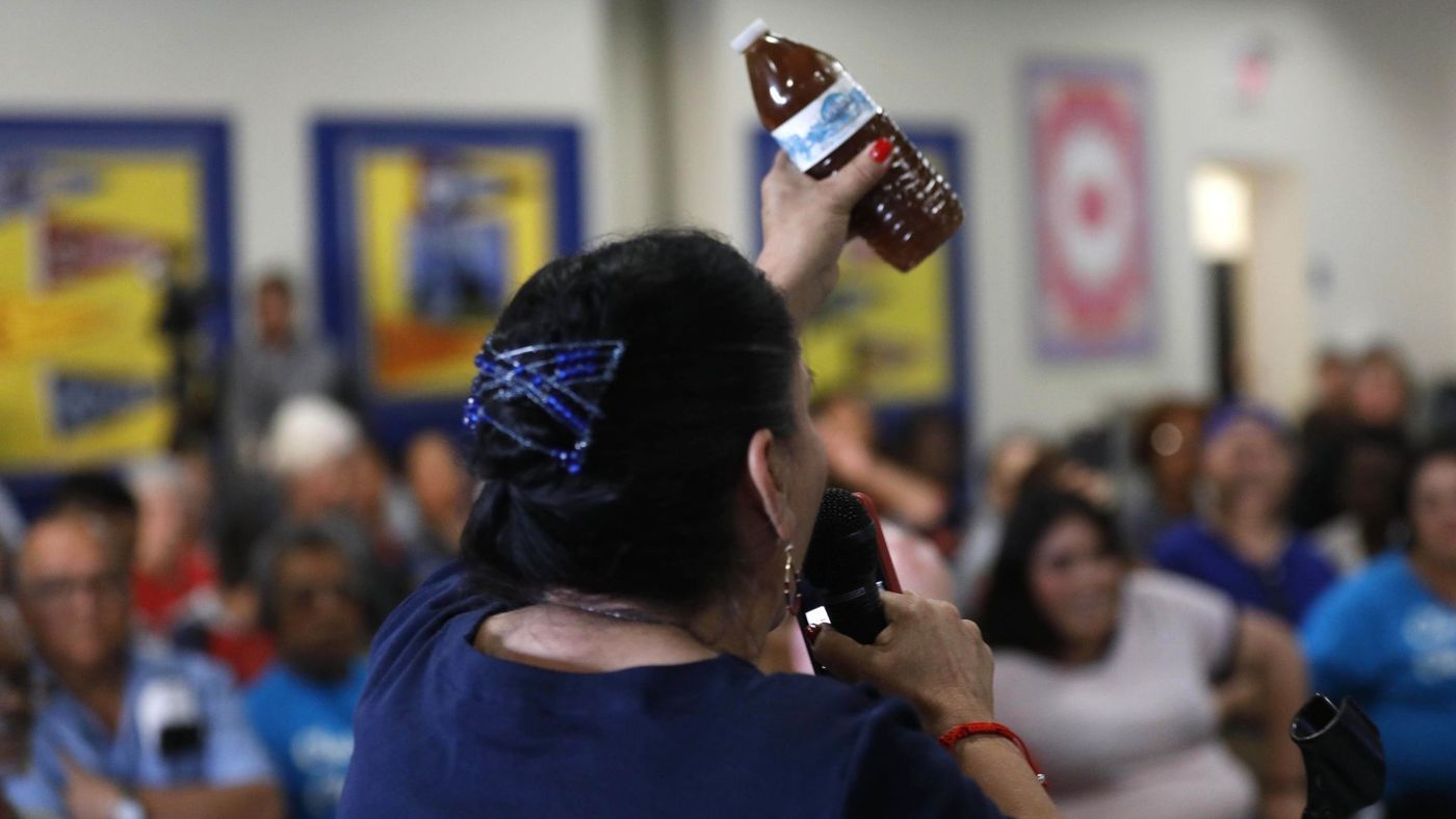 During a town hall June 18, 2018, Compton resident Maria Villarreal holds up a bottle containing brown water that she said came from the tap in her home. (Credit: Genaro Molina / Los Angeles Times)