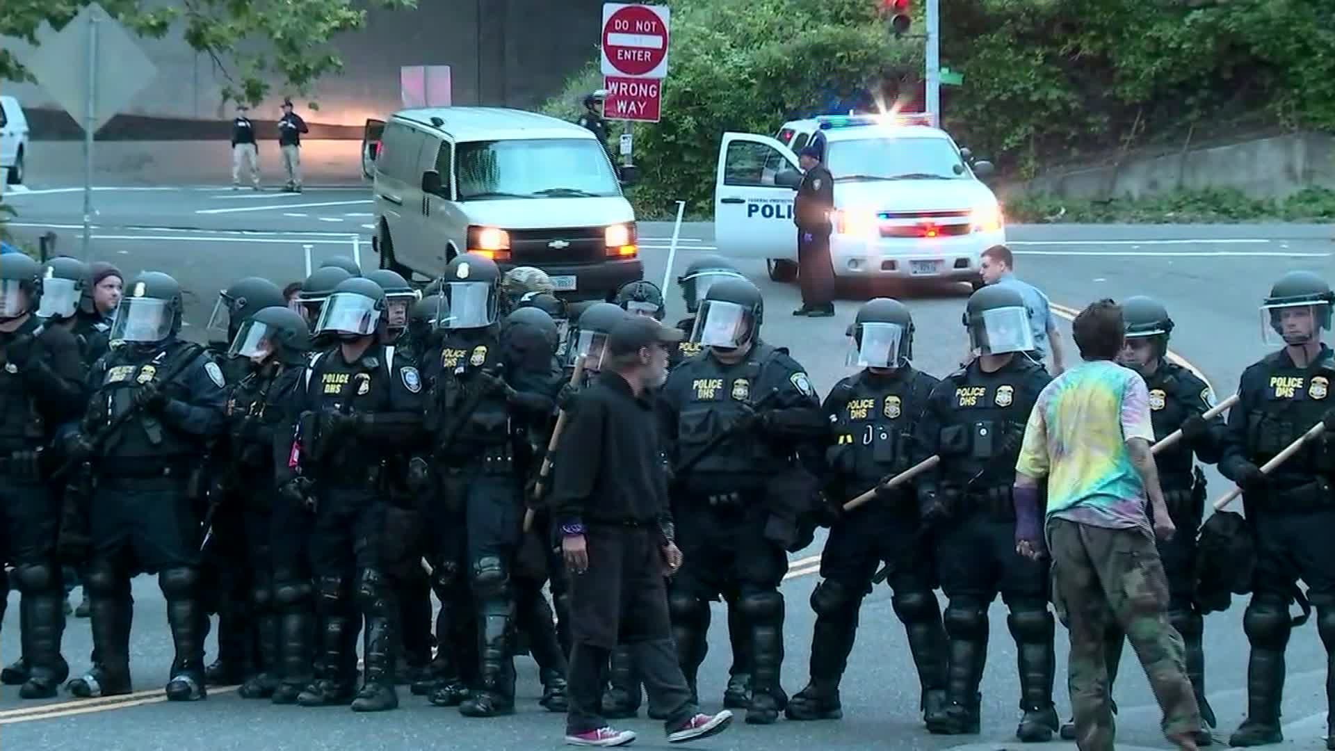 Protesters stand on June 28, 2018, near officers in riot gear as they block an entrance to the Portland ICE facility. (Credit: KPTV/CNN)