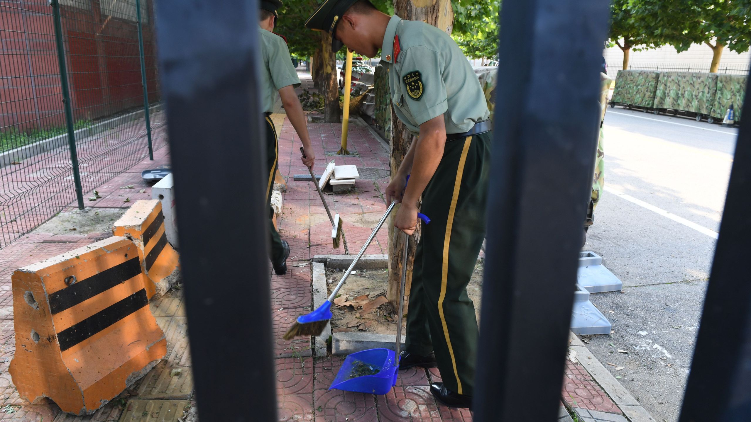 Chinese paramilitary police clean up broken glass and debris outside the US embassy compound in Beijing on July 26, 2018 following a blast near the embassy premises. (Credit: GREG BAKER/AFP/Getty Images)