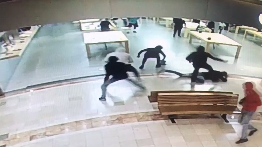 Burglars escape the scene of an Apple store in Costa Mesa as one of them kicks a man on the ground, on July 23, 2018. (Credit: Costa Mesa Police Department)