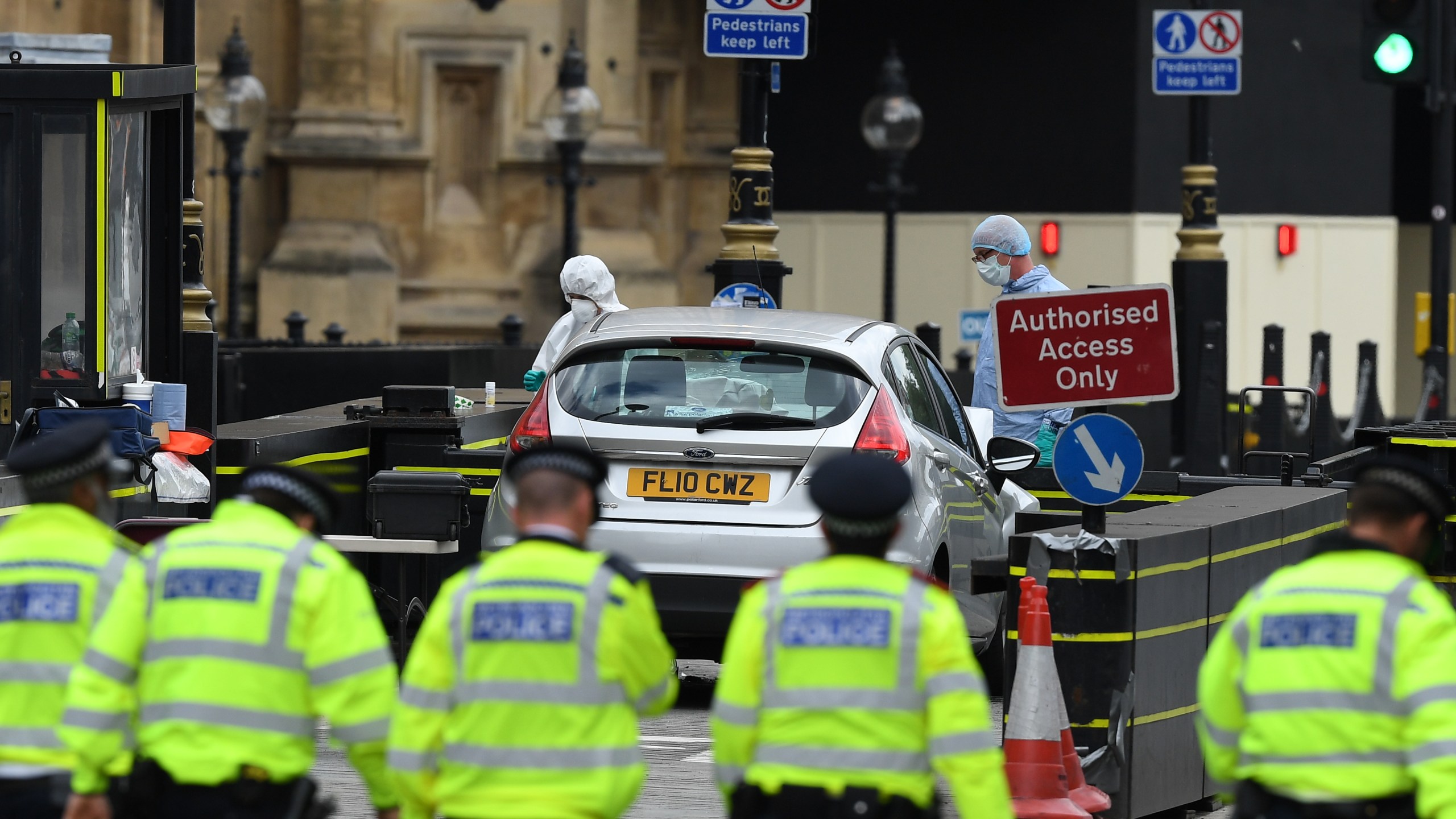 Police officers search the scene as forensic officers work on the vehicle that crashed into security barriers outside the Houses of Parliament in London on Aug. 14, 2018. (Credit: Leon Neal/Getty Images)