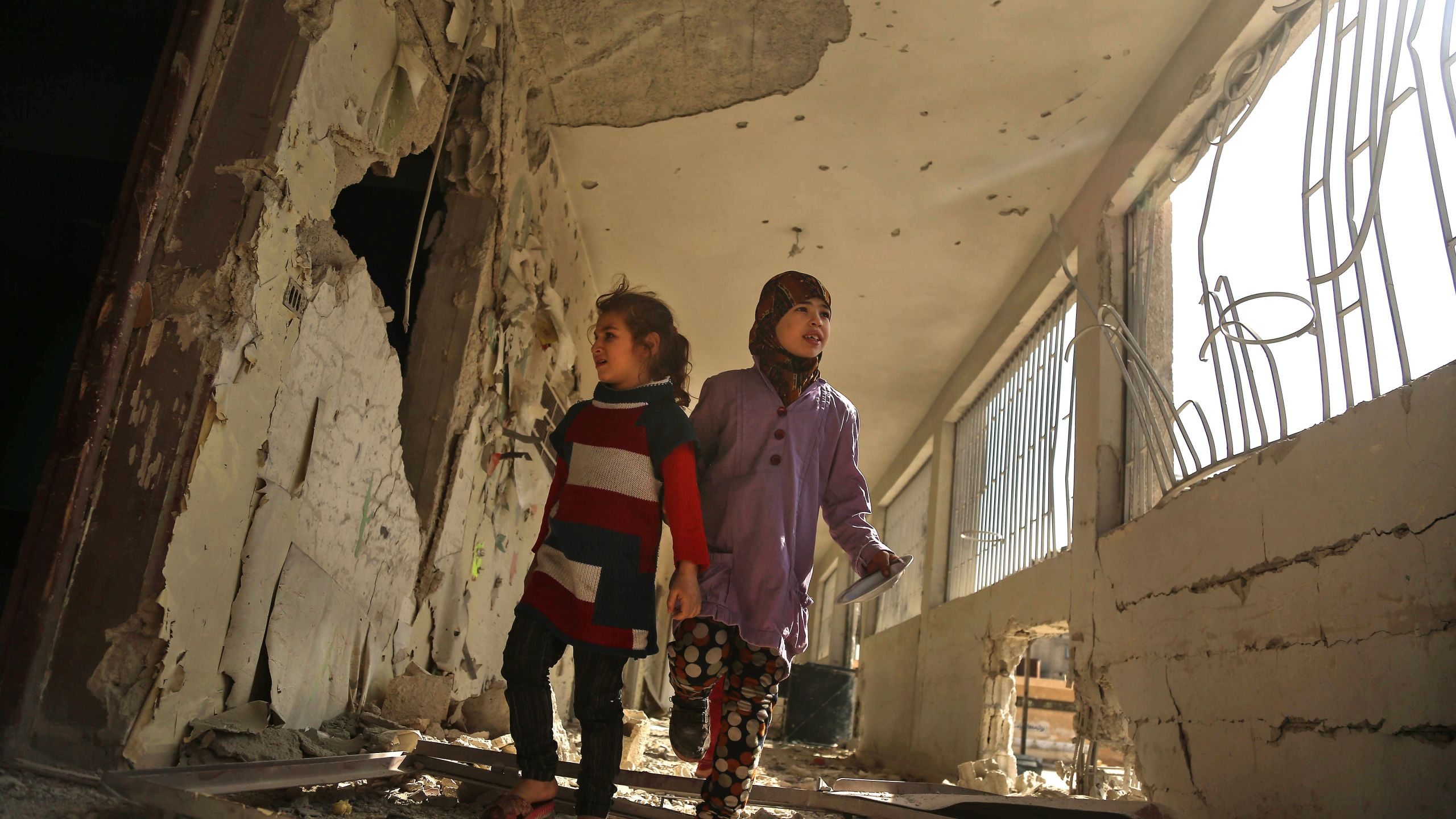 Syrian children tour their damaged school on Nov. 9, 2017, in the besieged rebel-held Eastern Ghouta town of Saqba, on the outskirts of the Syrian capital Damascus, following air raids by government forces on the area the previous day. (Credit: AMER ALMOHIBANY/AFP/Getty Images)