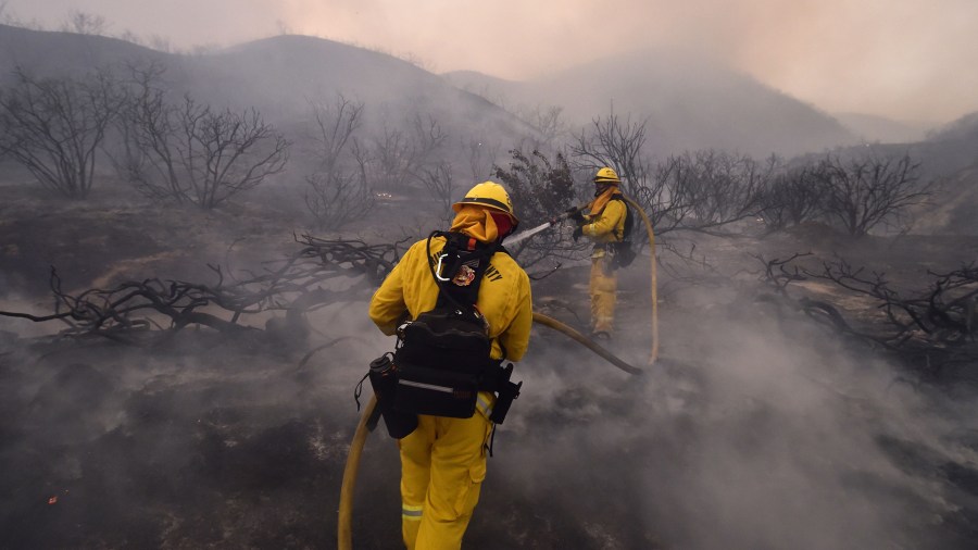 Riverside County firefighters douse embers from the Holy Fire in Lake Elsinore on Aug. 9, 2018. (Credit: ROBYN BECK/AFP/Getty Images)