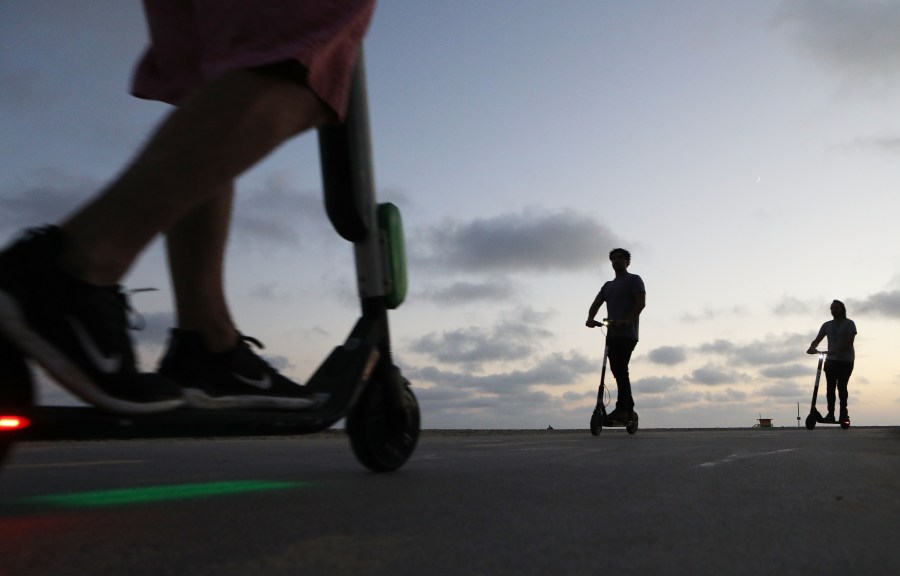 People ride shared dockless electric scooters along Venice Beach on Aug. 13, 2018. (Credit: Mario Tama/Getty Images)