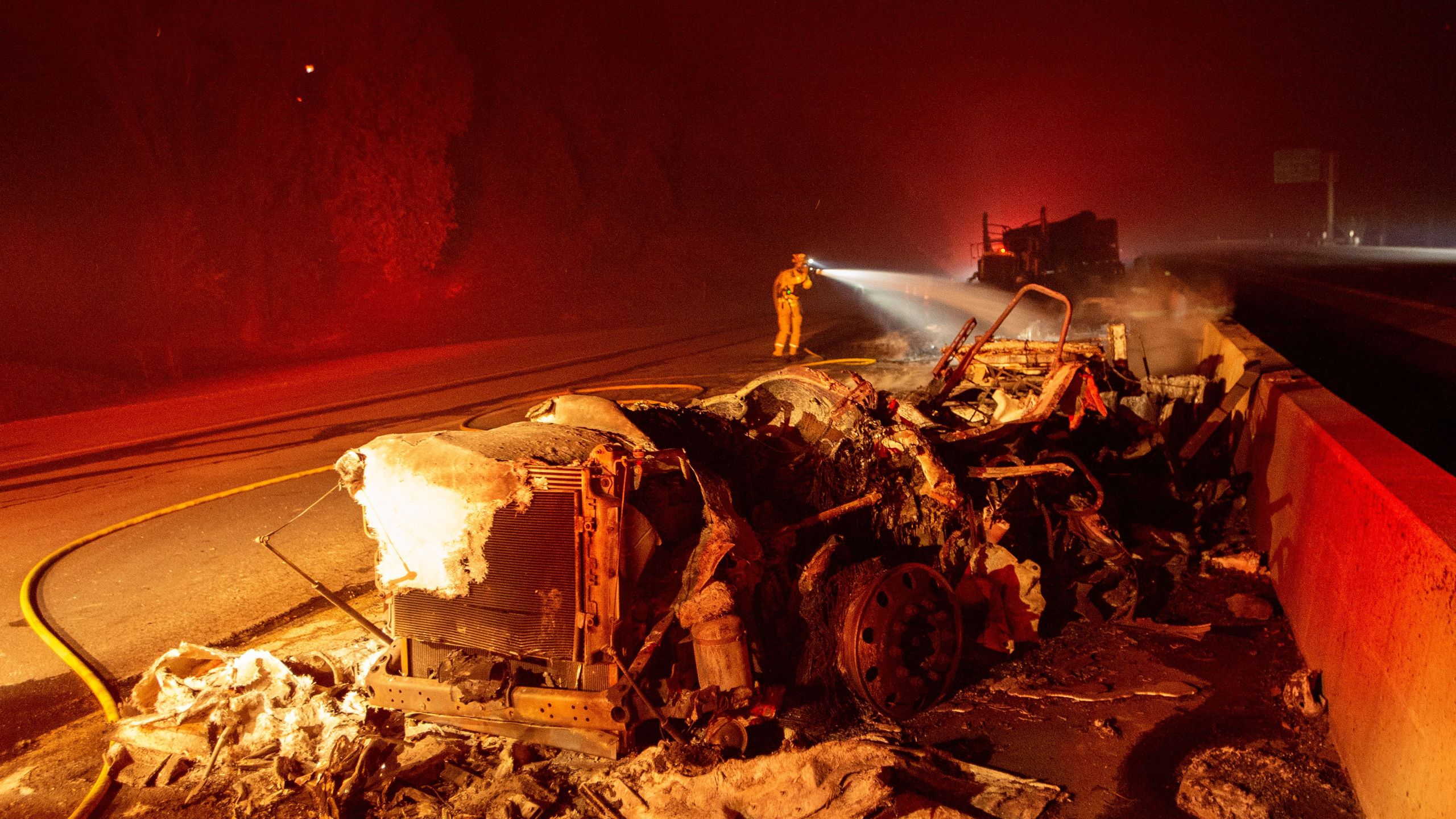 A firefighter sprays down a burned big rig truck that was abandoned along Interstate 5 as the Delta Fire tore through the region in Delta on Sept. 5, 2018. (JOSH EDELSON/AFP/Getty Images)