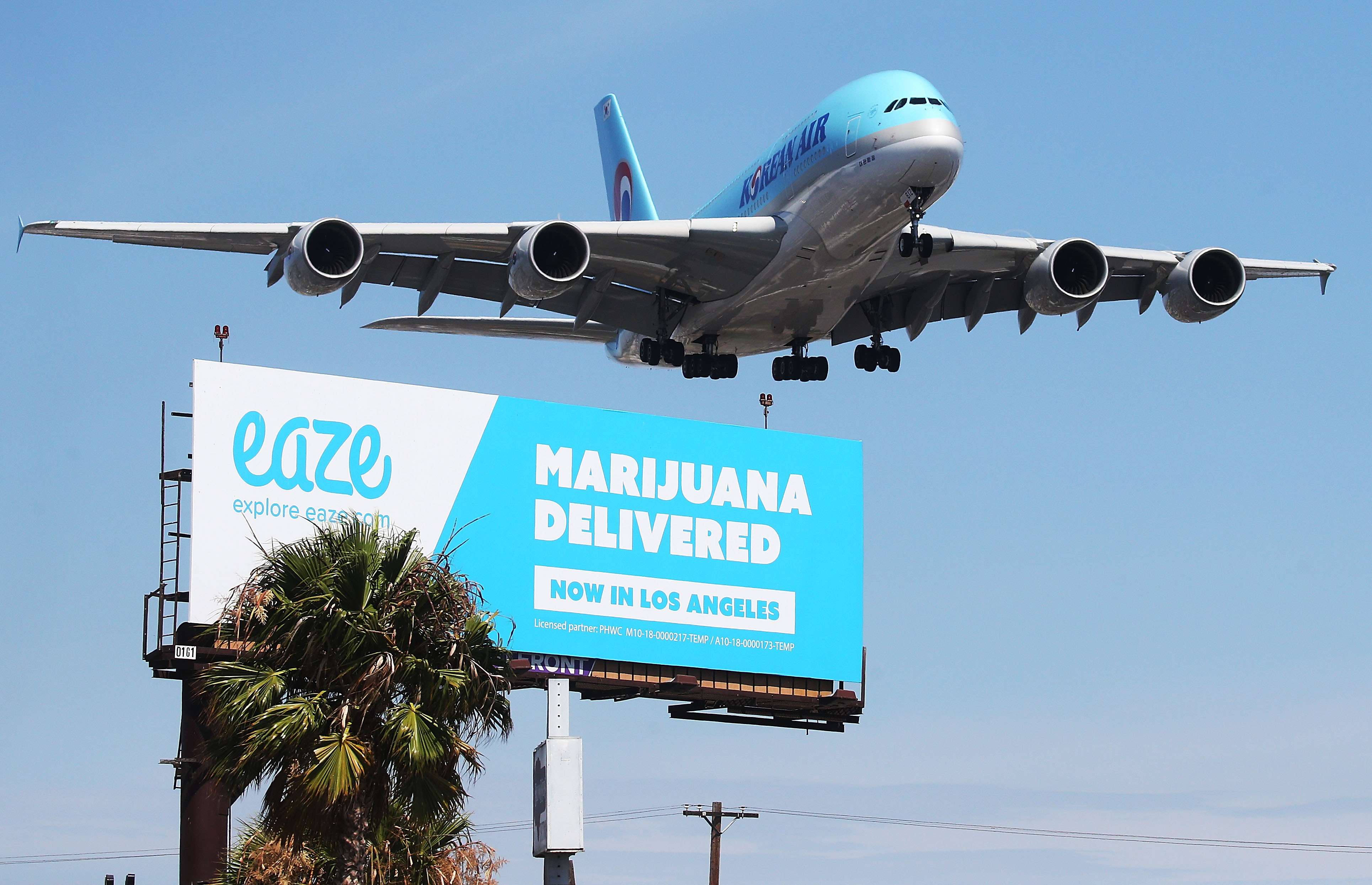 An airplane flies above a billboard advertising the marijuana delivery service Eaze, as the plane approaches landing at Los Angeles International Airport on July 12, 2018, in Los Angeles. (Credit: Mario Tama/Getty Images)