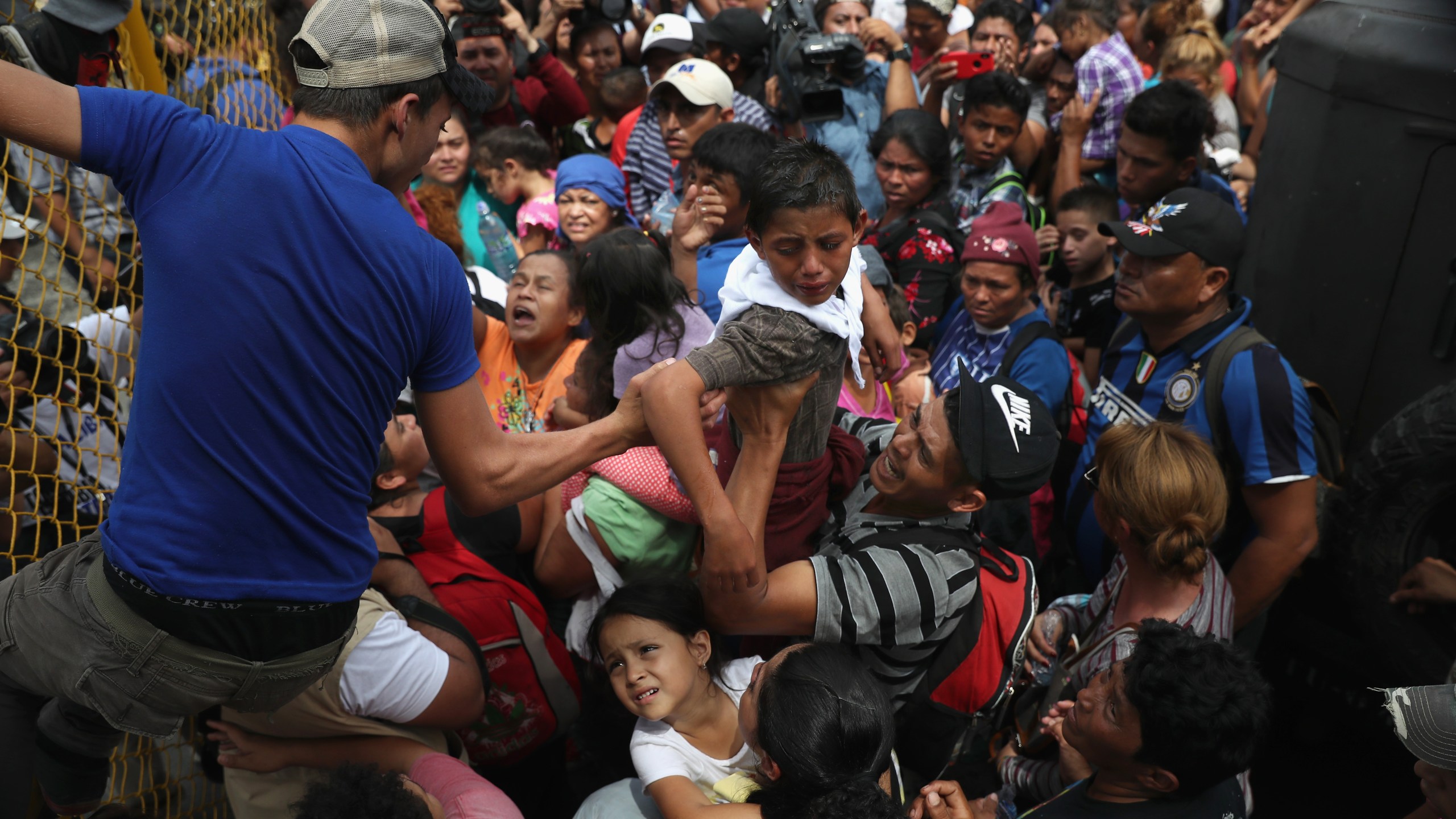 Children in a migrant caravan are lifted over a gate at the Guatemala-Mexico border on Oct. 19, 2018, in Ciudad Tecun Uman, Guatemala. (Credit: John Moore / Getty Images)