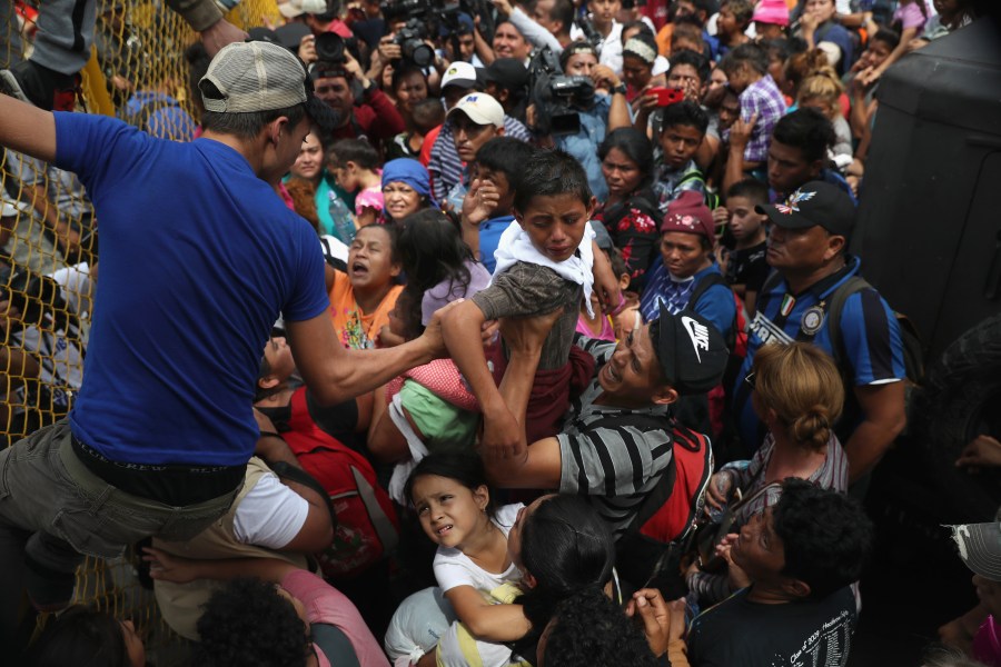 Children in a migrant caravan are lifted over a gate at the Guatemala-Mexico border on Oct. 19, 2018, in Ciudad Tecun Uman, Guatemala. (Credit: John Moore / Getty Images)