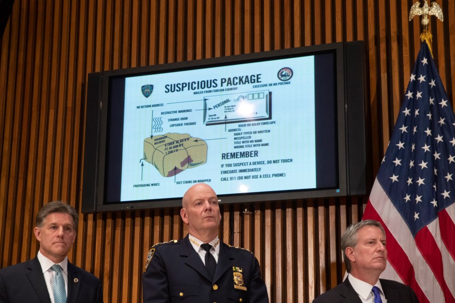 A monitor displays information about suspicious packages as NYPD Chief of Department Terence Monahan, center, and New York City Mayor Bill de Blasio, right, look on during a press conference at NYPD headquarters regarding the recent package bombings, Oct. 25, 2018. (Credit: Drew Angerer / Getty Images)