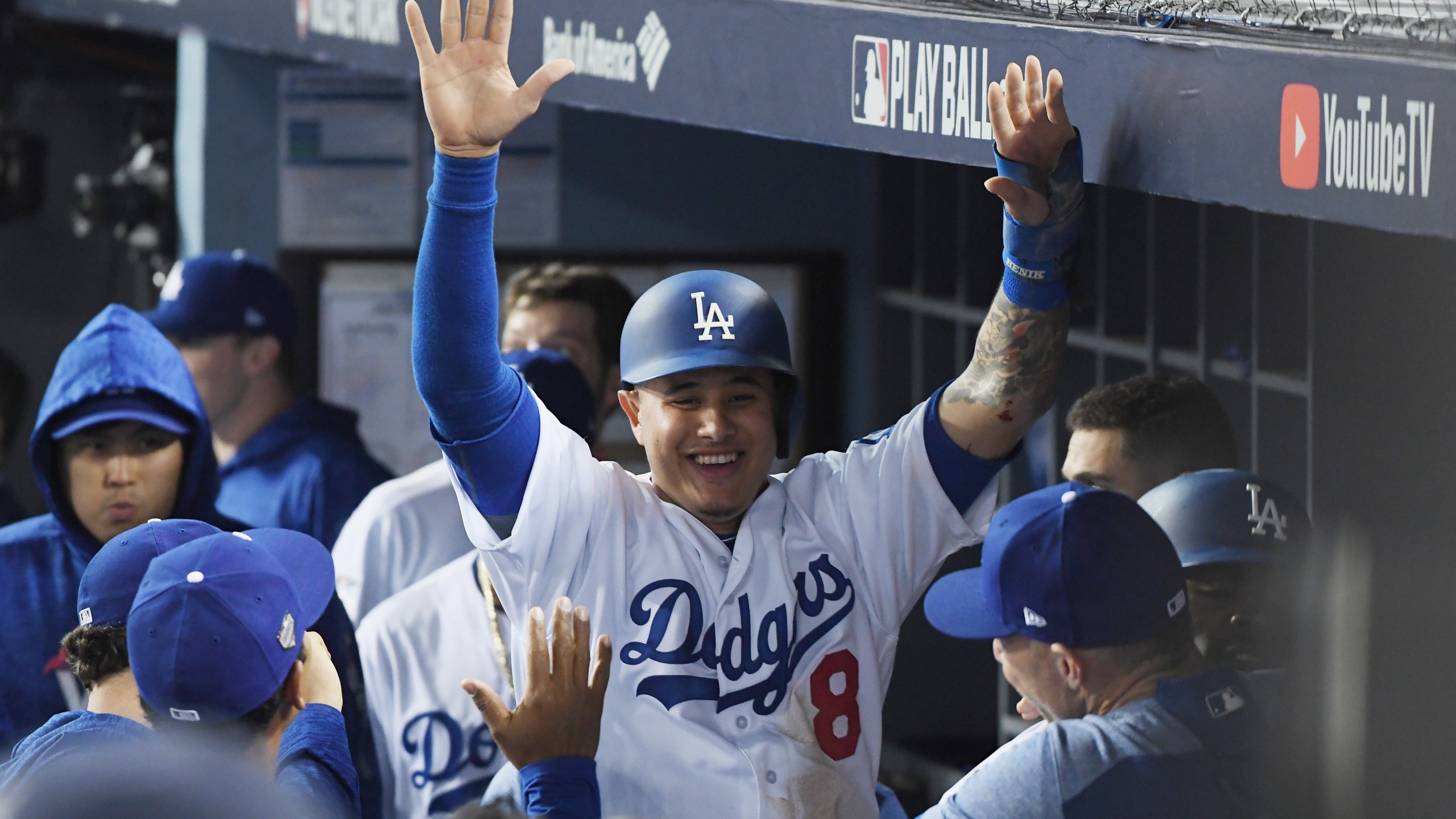 Manny Machado #8 of the Los Angeles Dodgers celebrates with teammates in the dugout after scoring on a three-run home run hit by Yasiel Puig #66 in the sixth inning of Game 4 of the 2018 World Series against the Boston Red Sox at Dodger Stadium on Oct. 27, 2018 in Los Angeles. (Credit: Harry How/Getty Images)