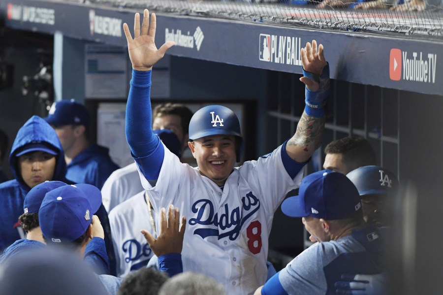 Manny Machado #8 of the Los Angeles Dodgers celebrates with teammates in the dugout after scoring on a three-run home run hit by Yasiel Puig #66 in the sixth inning of Game 4 of the 2018 World Series against the Boston Red Sox at Dodger Stadium on Oct. 27, 2018 in Los Angeles. (Credit: Harry How/Getty Images)