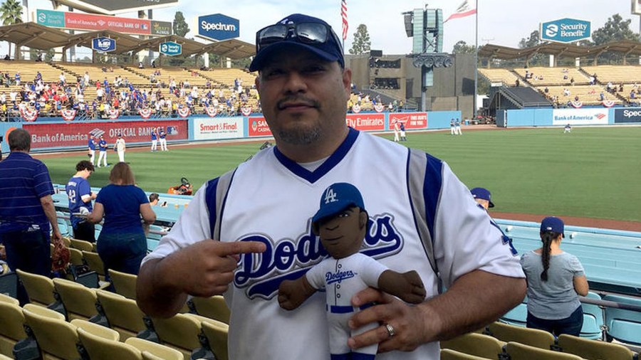 Isaac Tellez lives in Arkansas but he's a die-hard Dodgers fan. Here, he carries a stuffed doll of Yasiel Puig, who he calls 'Lil Puig,' into Game 5 of the 2018 World Series against the Boston Red Sox at Dodger Stadium in L.A. on Oct. 28, 2018. (Credit: Hailey Branson-Potts / Los Angeles Times)