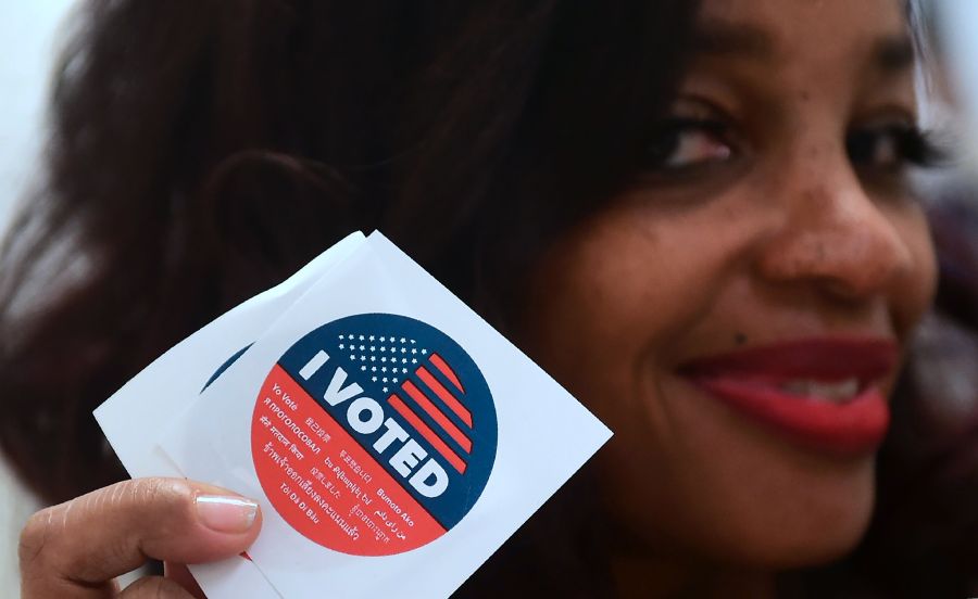 Jetoi Johnson displays California's multi-language "I Voted" sticker for those who vote at the Los Angeles County Registrar's Office in Norwalk on Nov. 5, 2018, a day ahead the midterm elections. (Credit: FREDERIC J. BROWN/AFP/Getty Images)