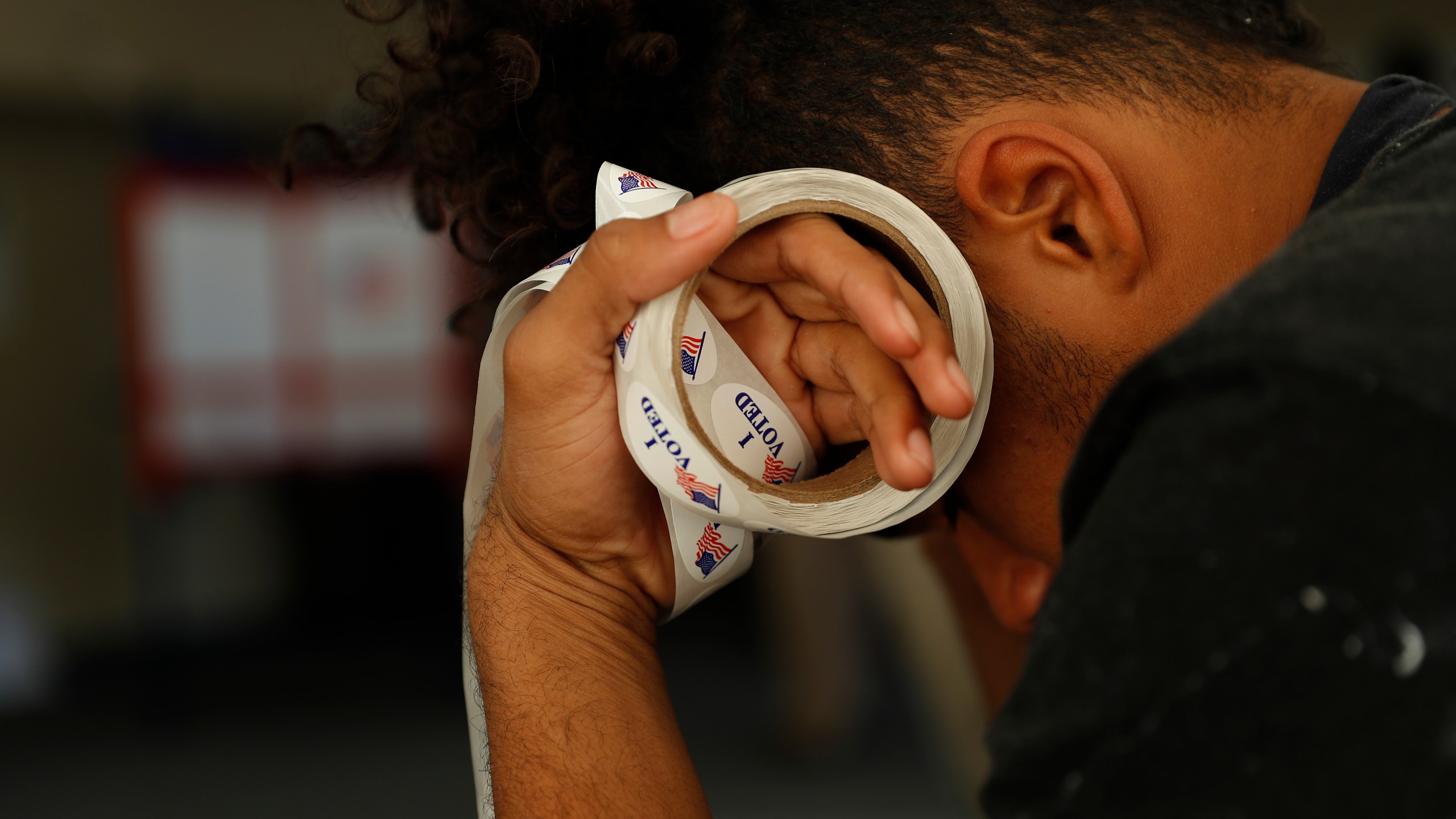 Poll worker Landen Lucas holds a roll of "I Voted" stickers at a polling place in Modesto on Nov. 6, 2018. (Credit: Stephen Lam / Getty Images)