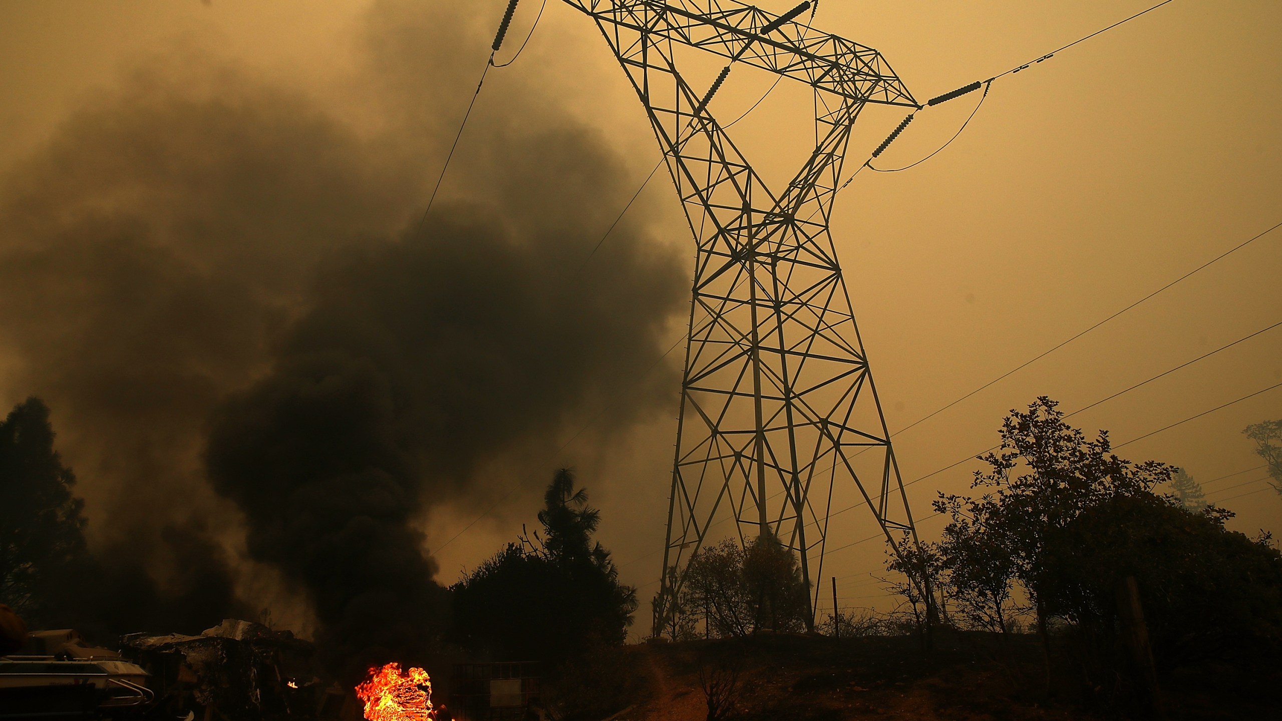 Smoke rises next to a power line tower after the Camp Fire moved through the area on November 9, 2018 in Big Bend, California. (Credit: Justin Sullivan/Getty Images)