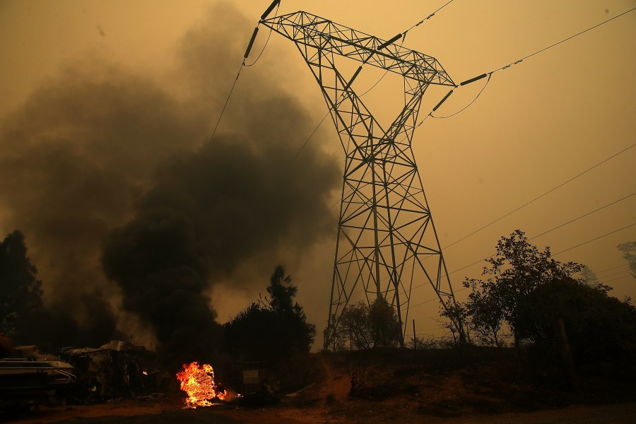 Smoke rises next to a power line tower after the Camp Fire moved through the area on November 9, 2018 in Big Bend, California. (Credit: Justin Sullivan/Getty Images)