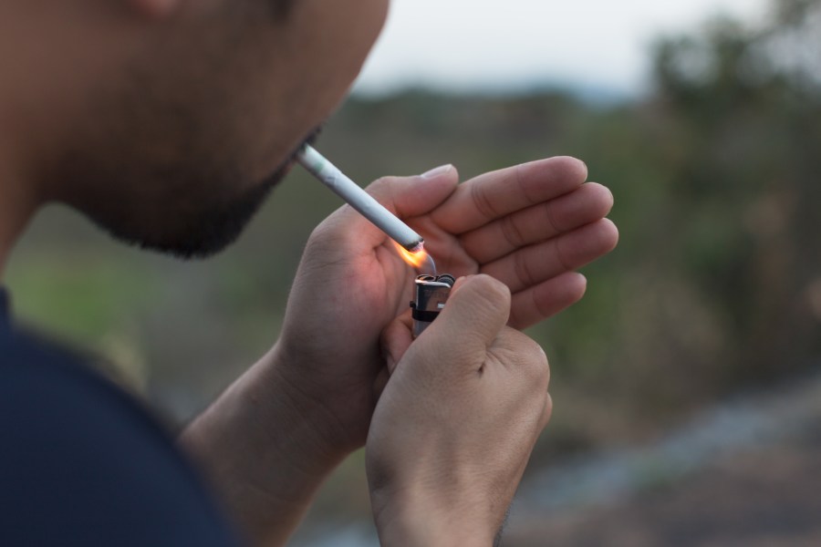 A man is seen lighting a cigarette in this file photo. (Credit: iStock/Getty Images Plus)