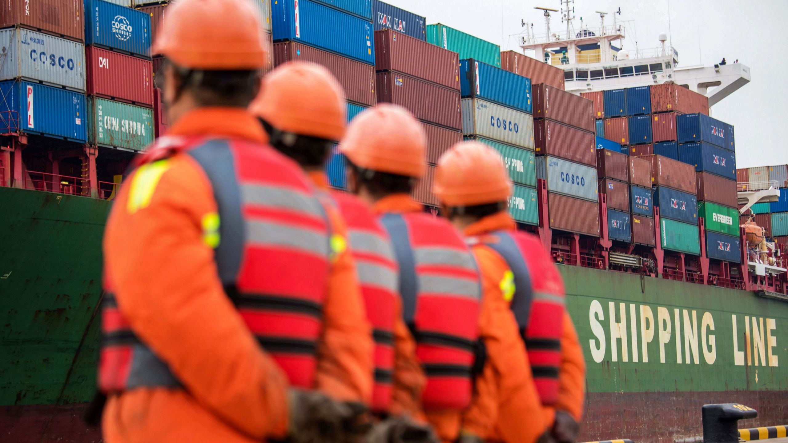 Employees look at a cargo ship at a port in Qingdao, east China's Shandong province on Nov. 8, 2018. (Credit: STR/AFP/Getty Images)