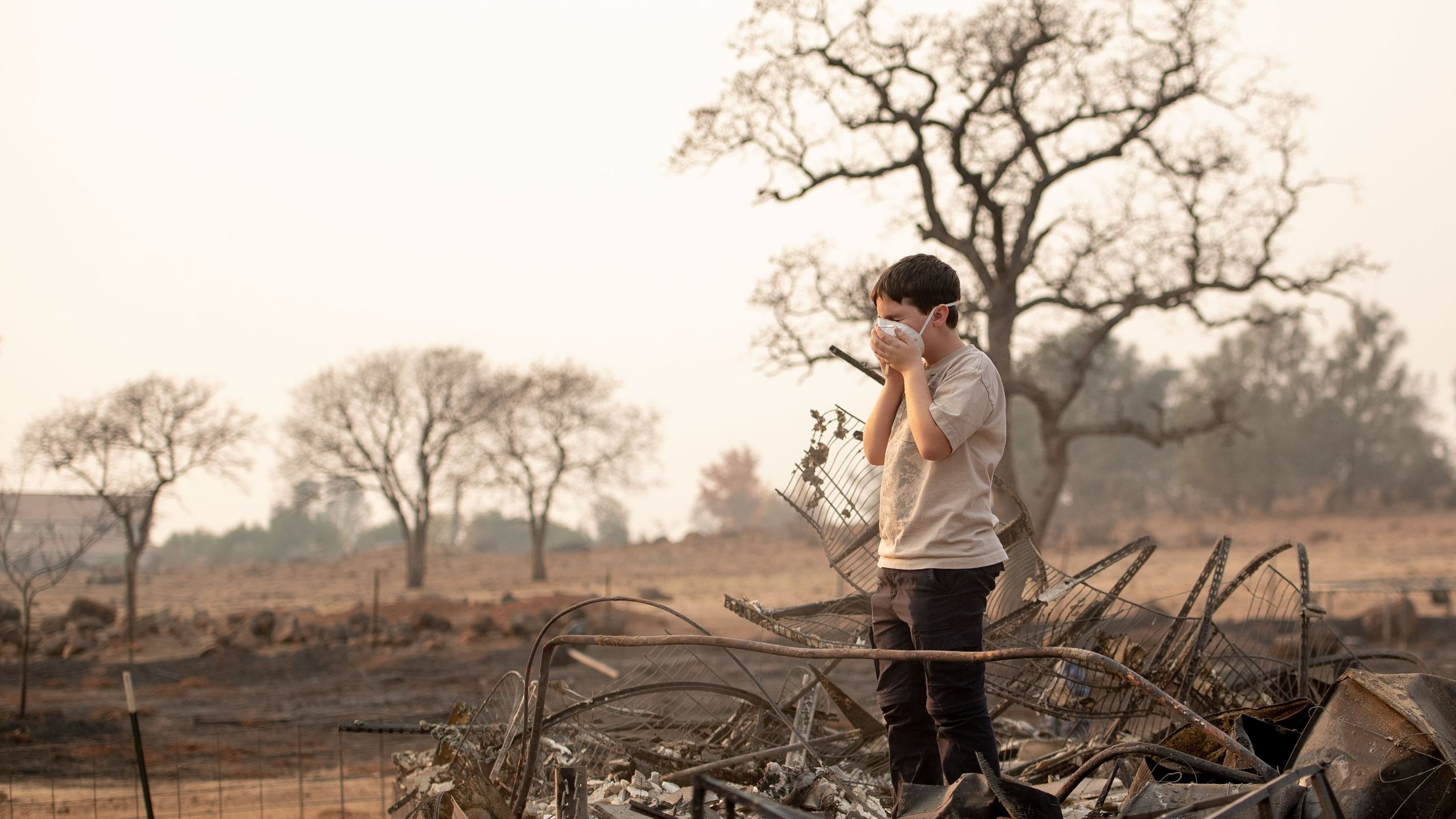 Jeremie Saylors, 11, adjusts his face mask while searching through the burned remains of his home in Paradise on Nov. 18, 2018. (Credit: Josh Edelson / AFP / Getty Images)