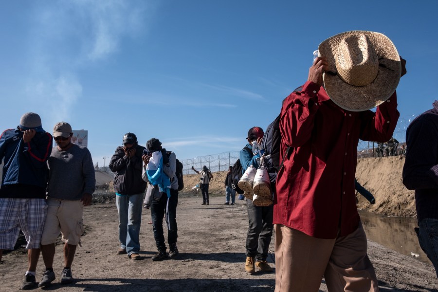 Central American migrants cover their faces next to the Tijuana River near the El Chaparral border crossing in Tijuana, Mexico, after the U.S. Border Patrol threw tear gas to disperse them after an alleged verbal dispute on Nov. 25, 2018. (Credit: Guillermo Arias / AFP / Getty Images)