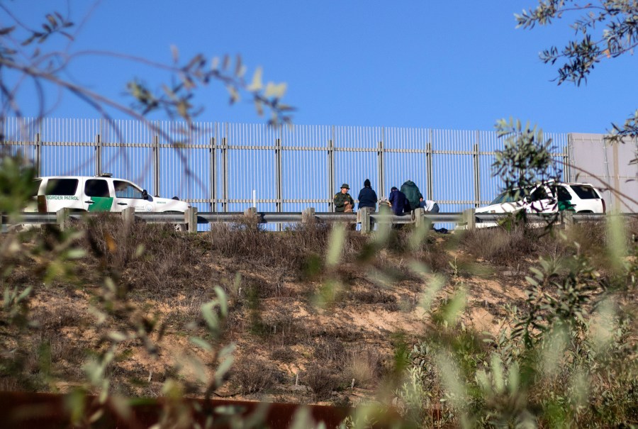 A group of migrants traveling in the Central American caravan are taken in custody by the U.S. Border Patrol after crossing the border fence into San Diego County, as seen from Playas de Tijuana, Mexico, on Dec. 12, 2018. (Credit: Guillermo Arias / AFP / Getty Images)