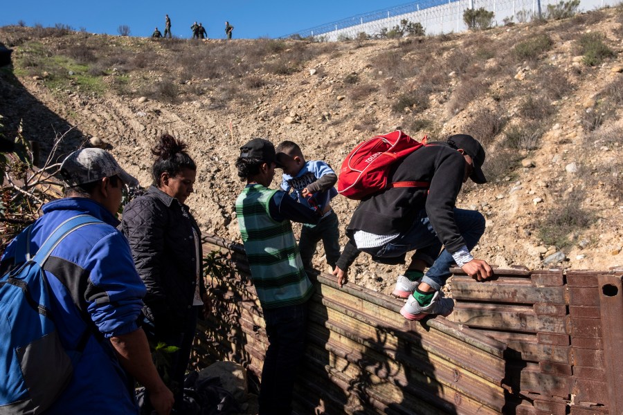 A group of Central American migrants -traveling in a caravan- cross the Mexico-US border fence to San Diego County, from Tijuana, on Dec. 16, 2018. (Credit: Guillermo Arias/AFP/Getty Images)