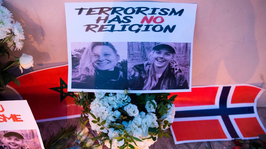 This picture taken on Dec. 21, 2018 shows photos of murdered Danish student Louisa Vesterager Jespersen on the Left and Nowegian Maren Ueland on the right, placed on top of flowers and between the flags of Morocco an Norway as Moroccans pay tribute to the Scandinavian victims. (Credit: Fadel Senna/AFP/Getty Images)