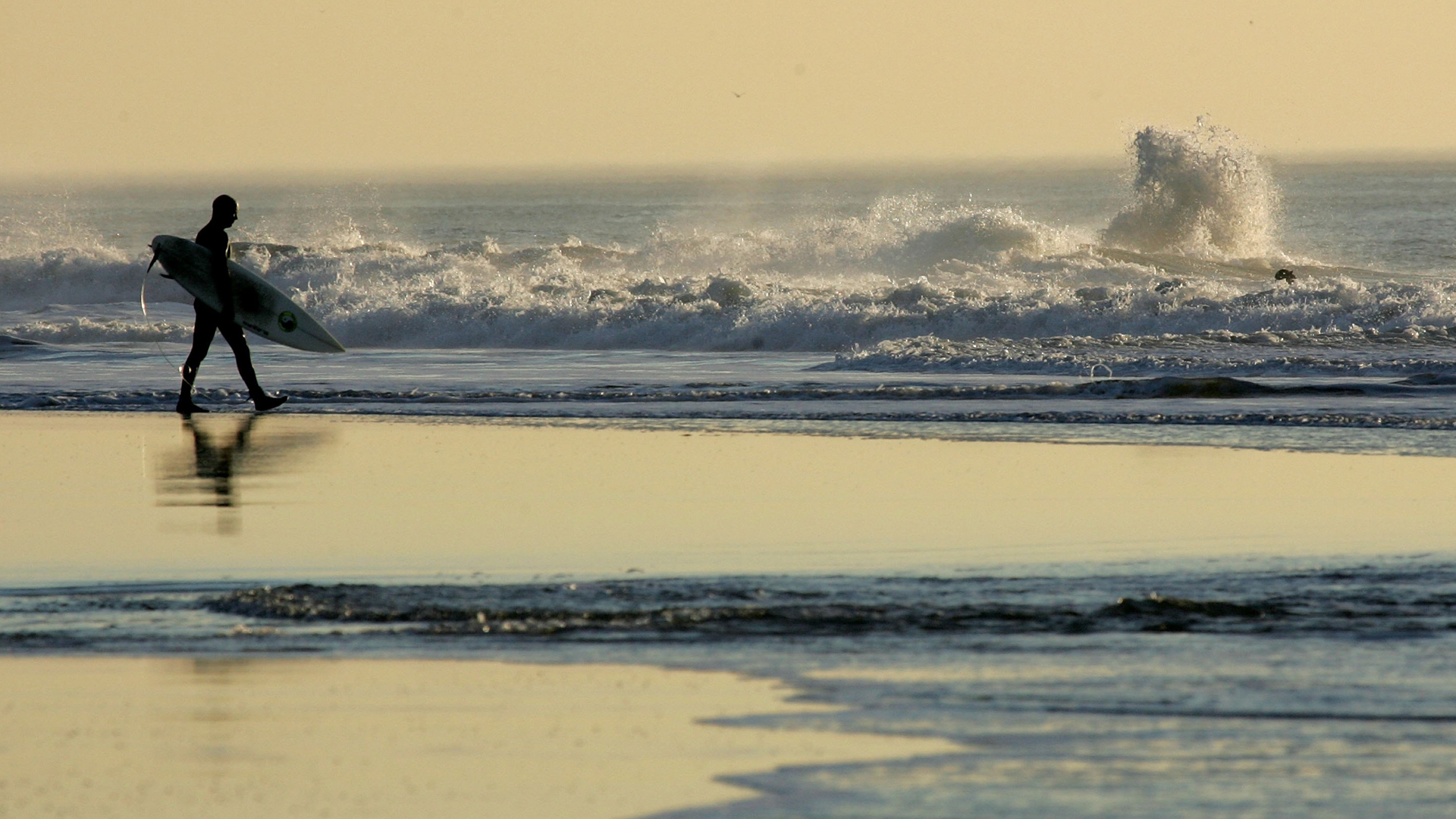 A surfer walks out into the water at Ocean Beach in San Francisco on Dec. 5, 2006. (Credit: Justin Sullivan/Getty Images)