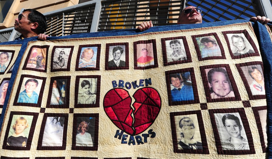 Abuse victim Jorgen Olsen, right, and supporter Glenn Gorospa, left, hold quilts bearing portraits of abused children while gathered outside the Cathedral of Our Lady of the Angels on Feb. 1, 2013. (Credit: Frederic J. Brown / AFP / Getty Images)