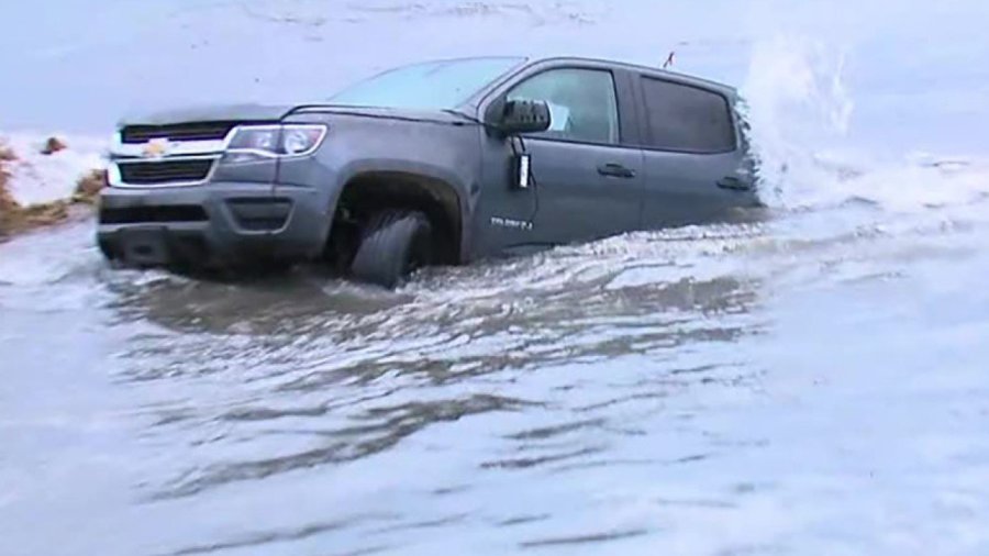 A tow truck was needed to pull a pickup truck out of the water Thursday morning after it was swept away by waves in La Jolla Shores. (Credit: KGTV via CNN)