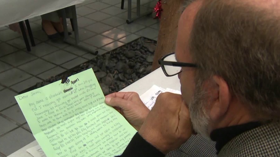 A volunteer reads through a Santa letter from a needy child in South L.A. during the U.S. Postal Service's 106th Annual Operation Santa on Dec. 12, 2018. (Credit: KTLA)