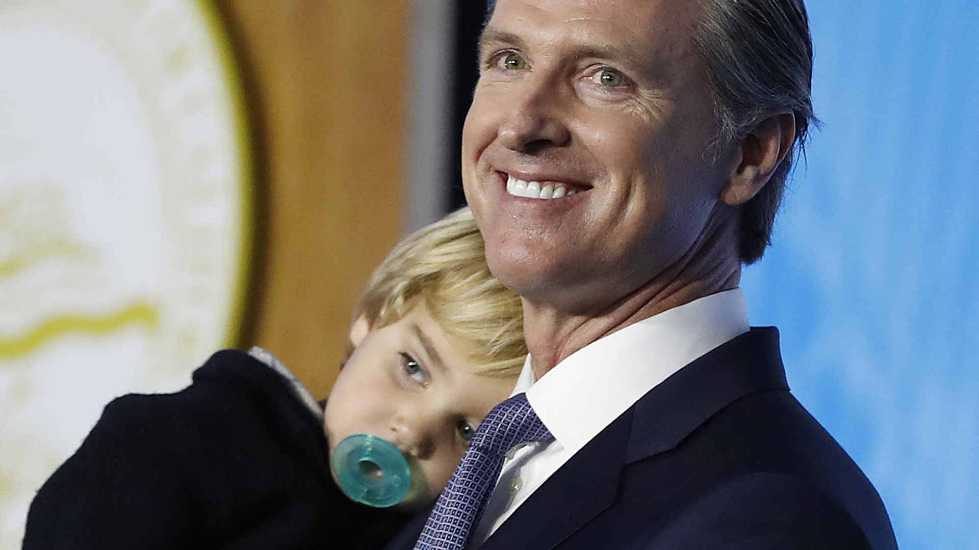 Gov. Gavin Newsom carries his 2-year-old son Dutch while delivering his inaugural address after being sworn in as the 40th governor of California on Jan. 7, 2019, in Sacramento. (Credit: Stephen Lam/Getty Images)