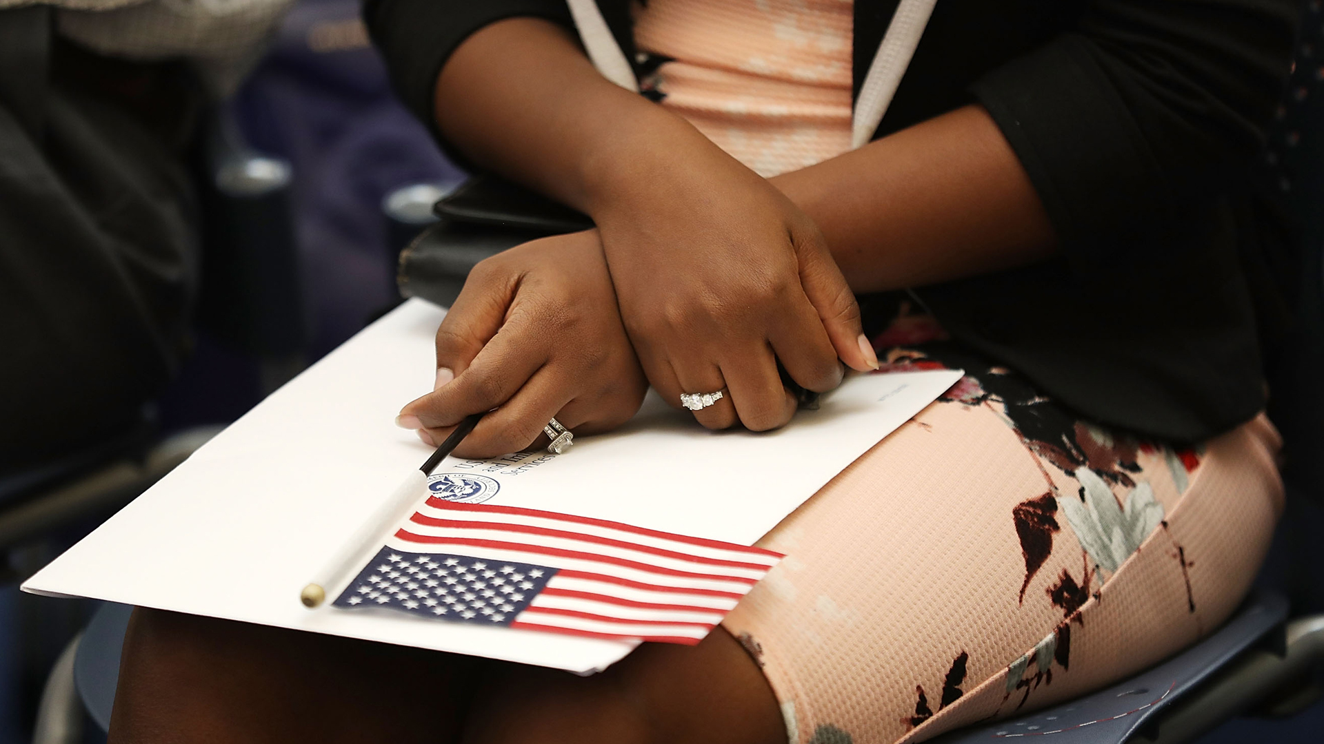 A woman holds an American flag during a ceremony to become an American citizen during a U.S. Citizenship and Immigration Services naturalization ceremony at the Miami field Office on Aug. 17, 2018, in Miami, Florida. (Credit: Joe Raedle/Getty Images)