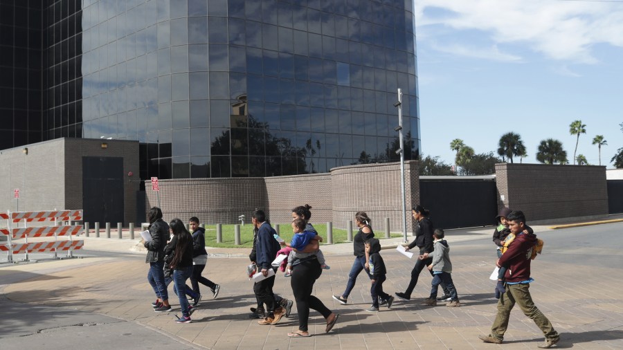 Immigrant asylum seekers walk past a U.S. federal courthouse after being released by U.S. Customs and Border Protection on Nov. 1, 2018 in McAllen, Texas. (Credit: John Moore/Getty Images)