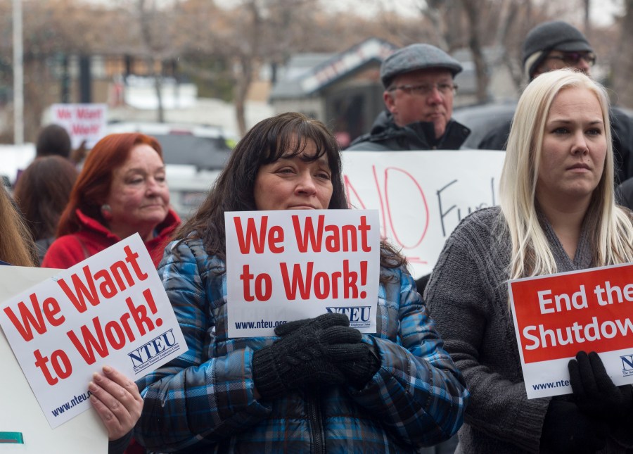 IRS employee Donna Orton (C) holds a sign protesting the government shutdown at the James V. Hansen Federal Building on January 10, 2019 in Ogden, Utah. (Credit: Natalie Behring/Getty Images)