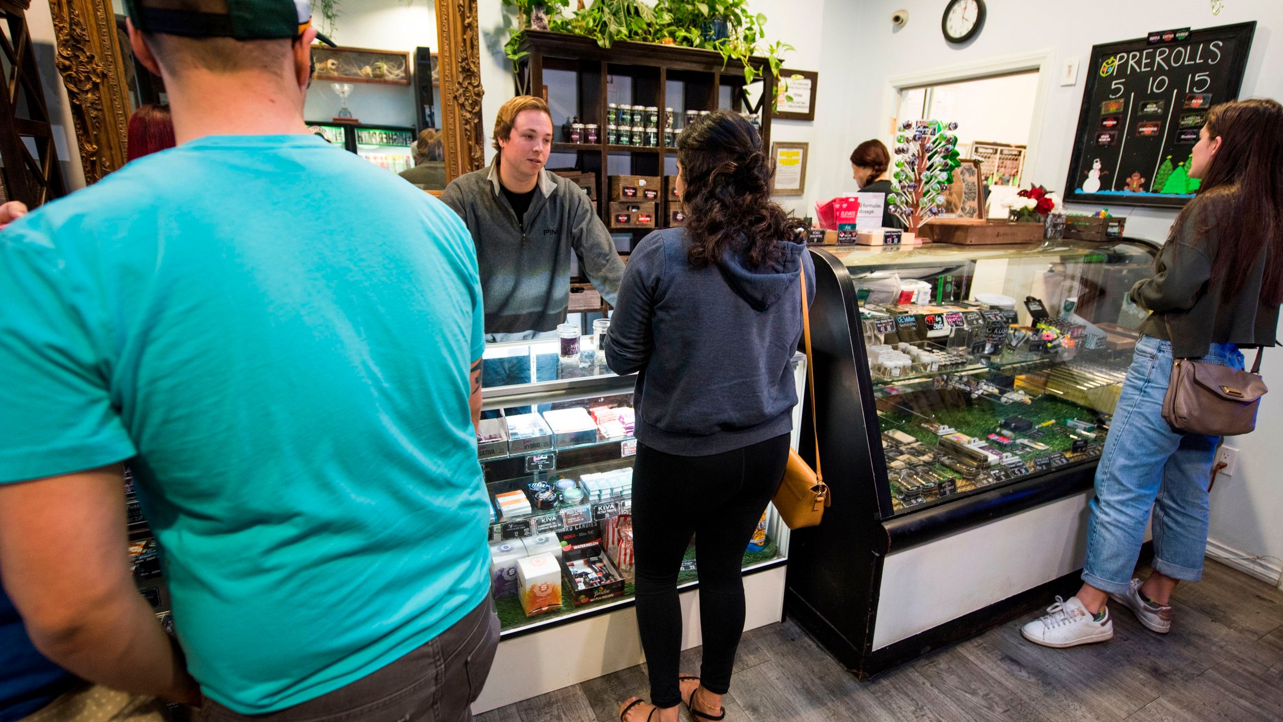 A budtender helps a customer as others wait their turn at the Higher Path medical marijuana dispensary in the San Fernando Valley area of Los Angeles on Dec. 27, 2017. (Credit: ROBYN BECK/AFP/Getty Images)