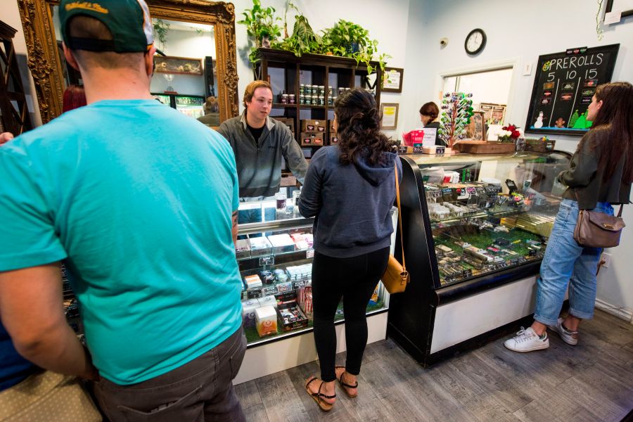 A budtender helps a customer as others wait their turn at the Higher Path medical marijuana dispensary in the San Fernando Valley area of Los Angeles on Dec. 27, 2017. (Credit: ROBYN BECK/AFP/Getty Images)